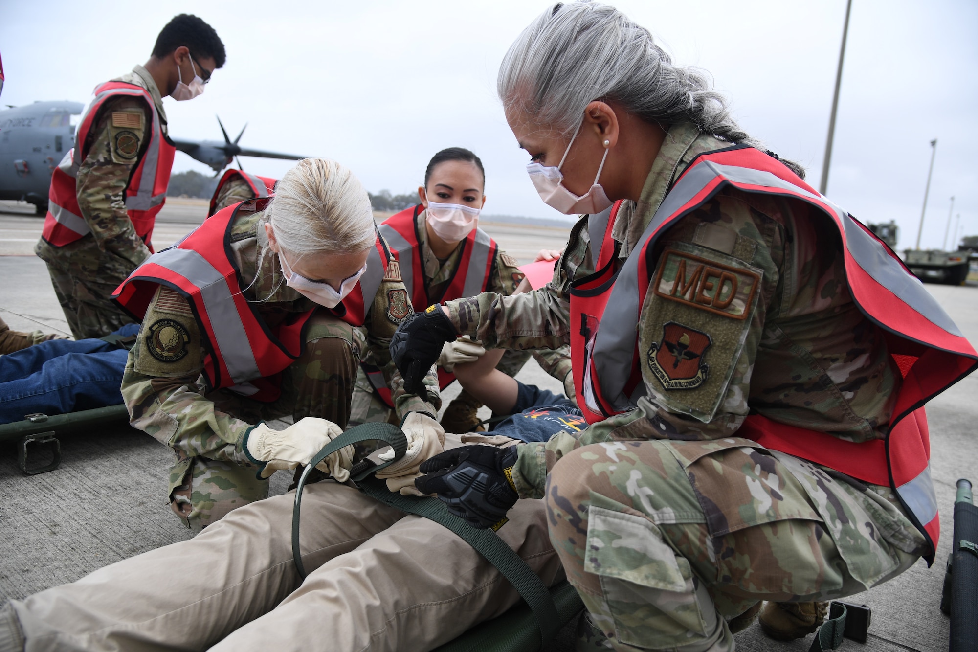 Members of the 81st Medical Group secure patients to stretchers during the National Disaster Medical System Exercise outside the 41st Aerial Port Squadron building at Keesler Air Force Base, Mississippi, Feb. 17, 2022. Keesler's Federal Coordination Center was activated and received more than 20 patients during the exercise scenario, which included the New Madrid Fault erupting, sparking an earthquake to occur in Tennessee causing extensive damage and injuring many people. Members of the 81st MDG participated in the event in order to better prepare themselves for real-world situations. (U.S. Air Force photo by Kemberly Groue)