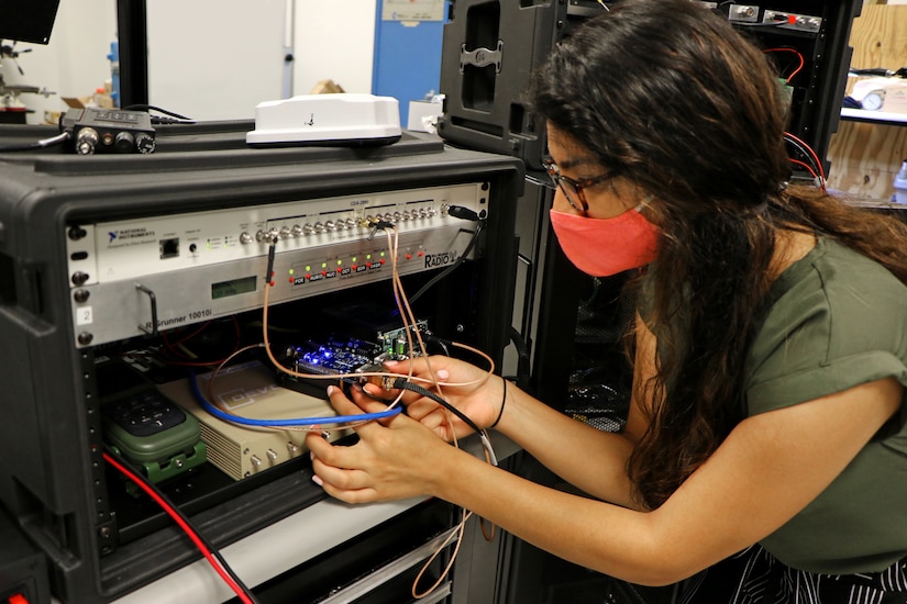 A woman works with electronic equipment in a small room.