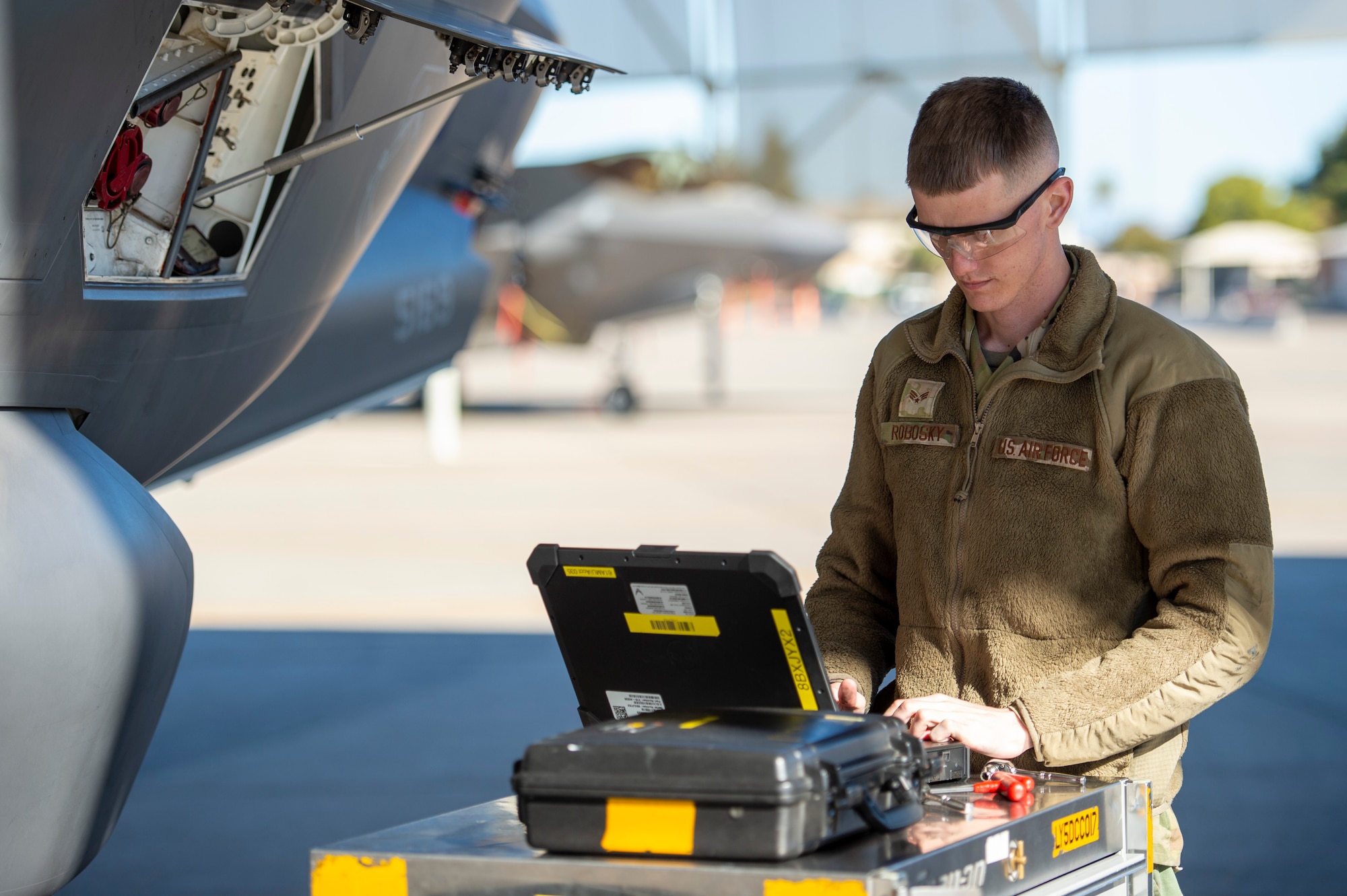 U.S. Air Force Senior Airman Aaron Robosky, 61st Aircraft Maintenance Unit F-35A Lightning II assistant dedicated crew chief, uses a wireless capable ruggedized laptop during an F-35 inspection Feb. 3, 2022, at Luke Air Force Base, Arizona. Prior to the wireless capable laptops being implemented in late 2021, flightline personnel had to leave their immediate work area, which created a time gap between task completion and the ability to update their maintenance systems. (U.S. Air Force photo by Staff Sgt. Collette Brooks)