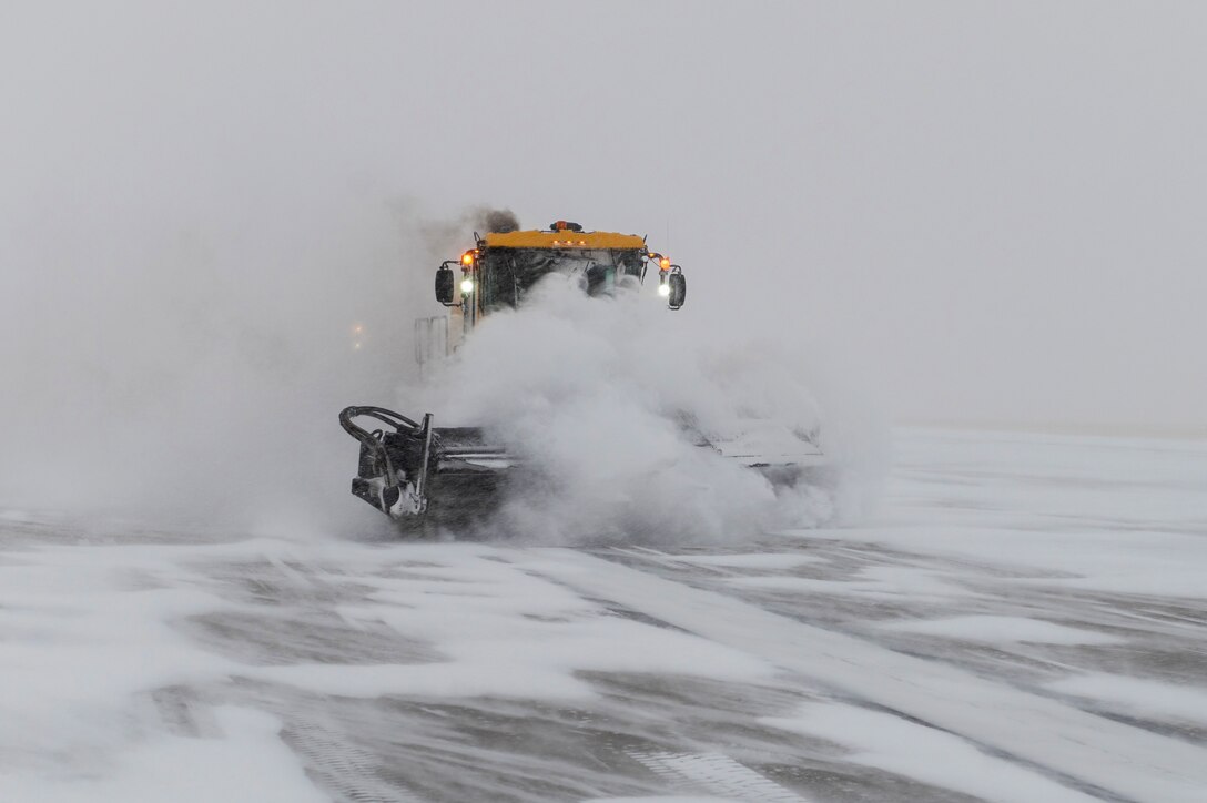 A plow removes snow along a flightline.