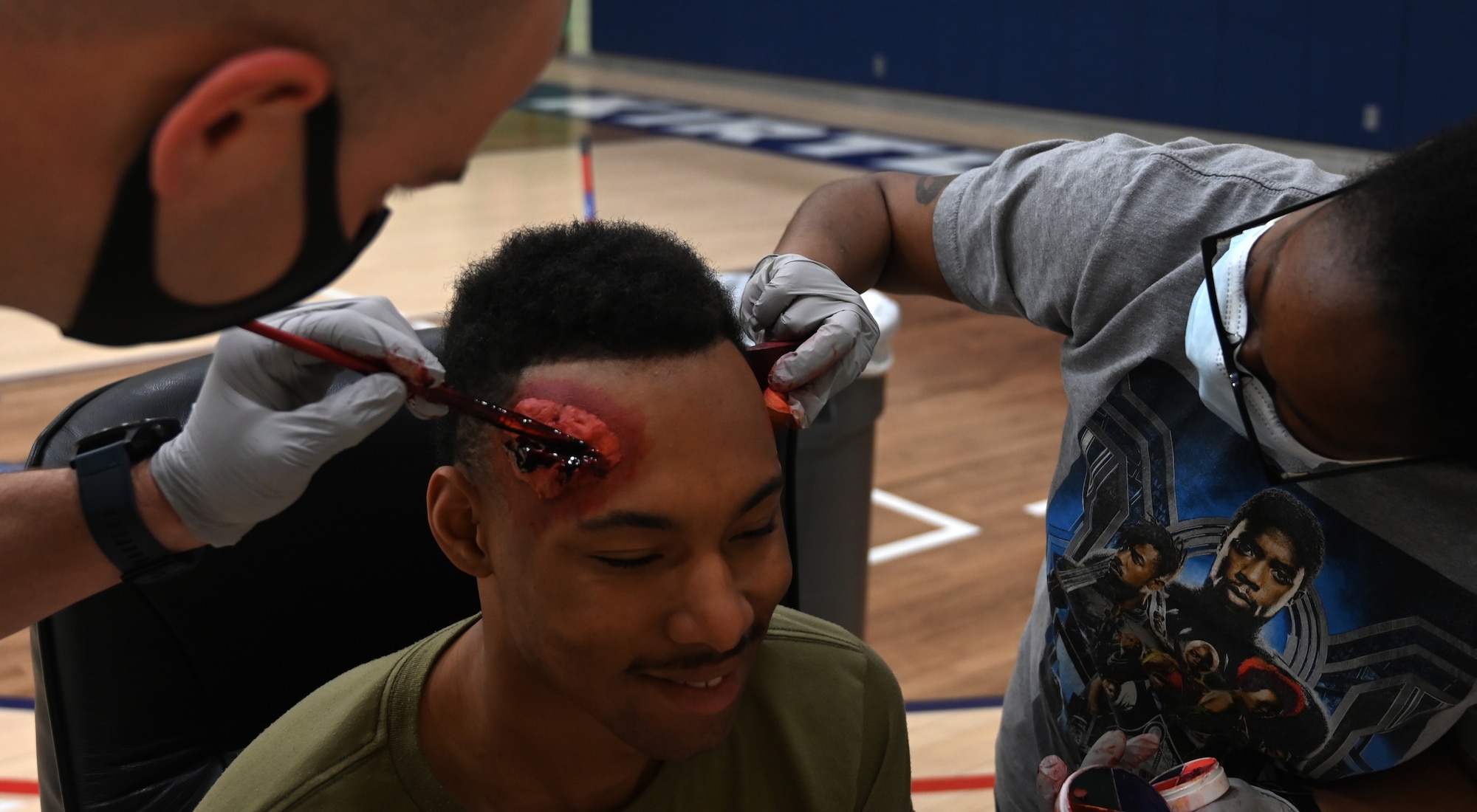 Makeup artists apply blood and tissue to role player