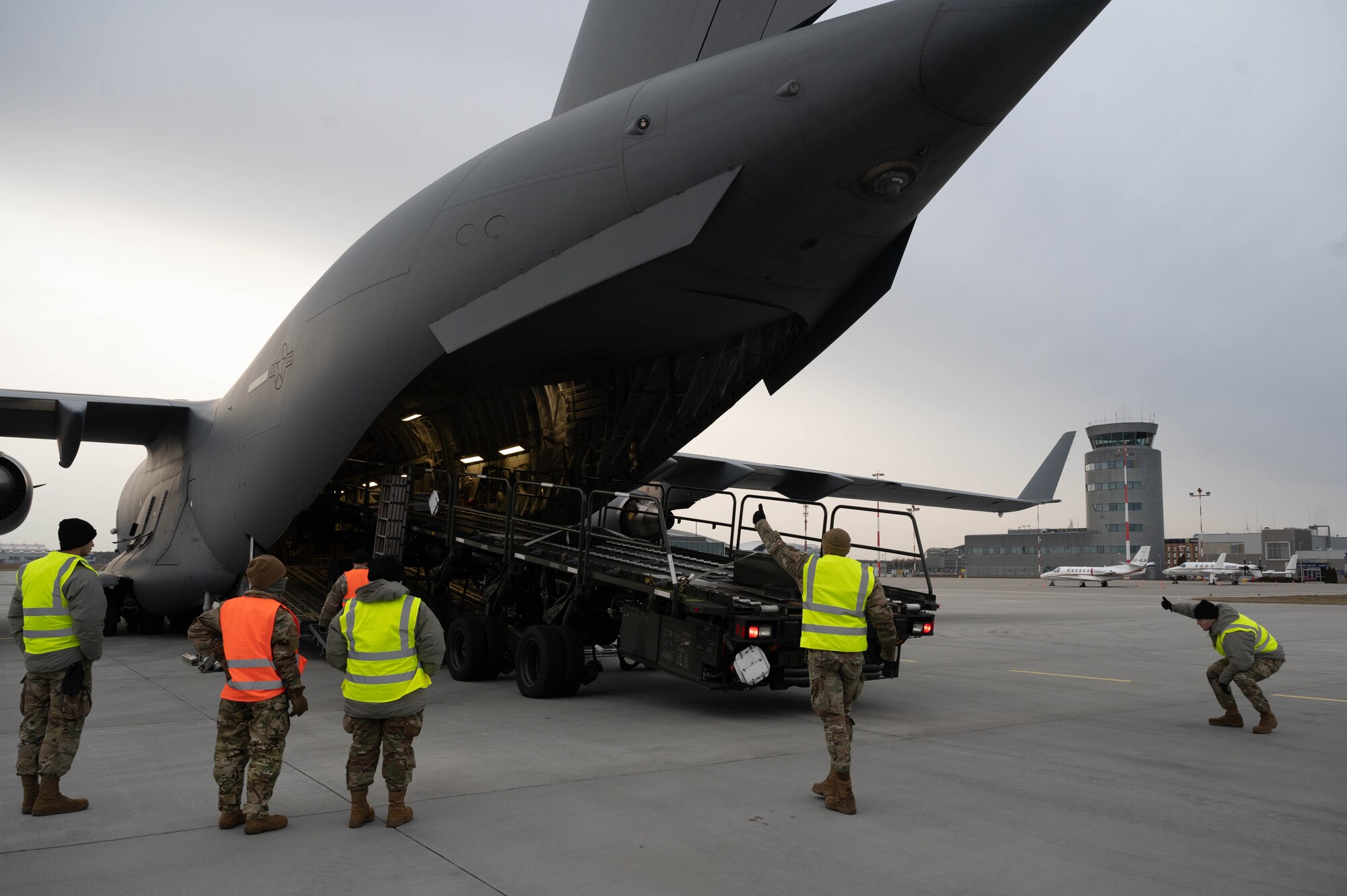 Airmen marshal a 60K aircraft cargo loader out of a C-17 Globemaster III.