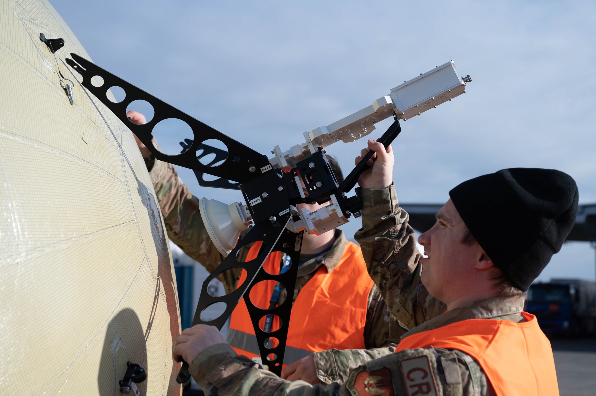 A member of the 435th CRS places a feeding horn on a ground antenna transmit and receive ball.
