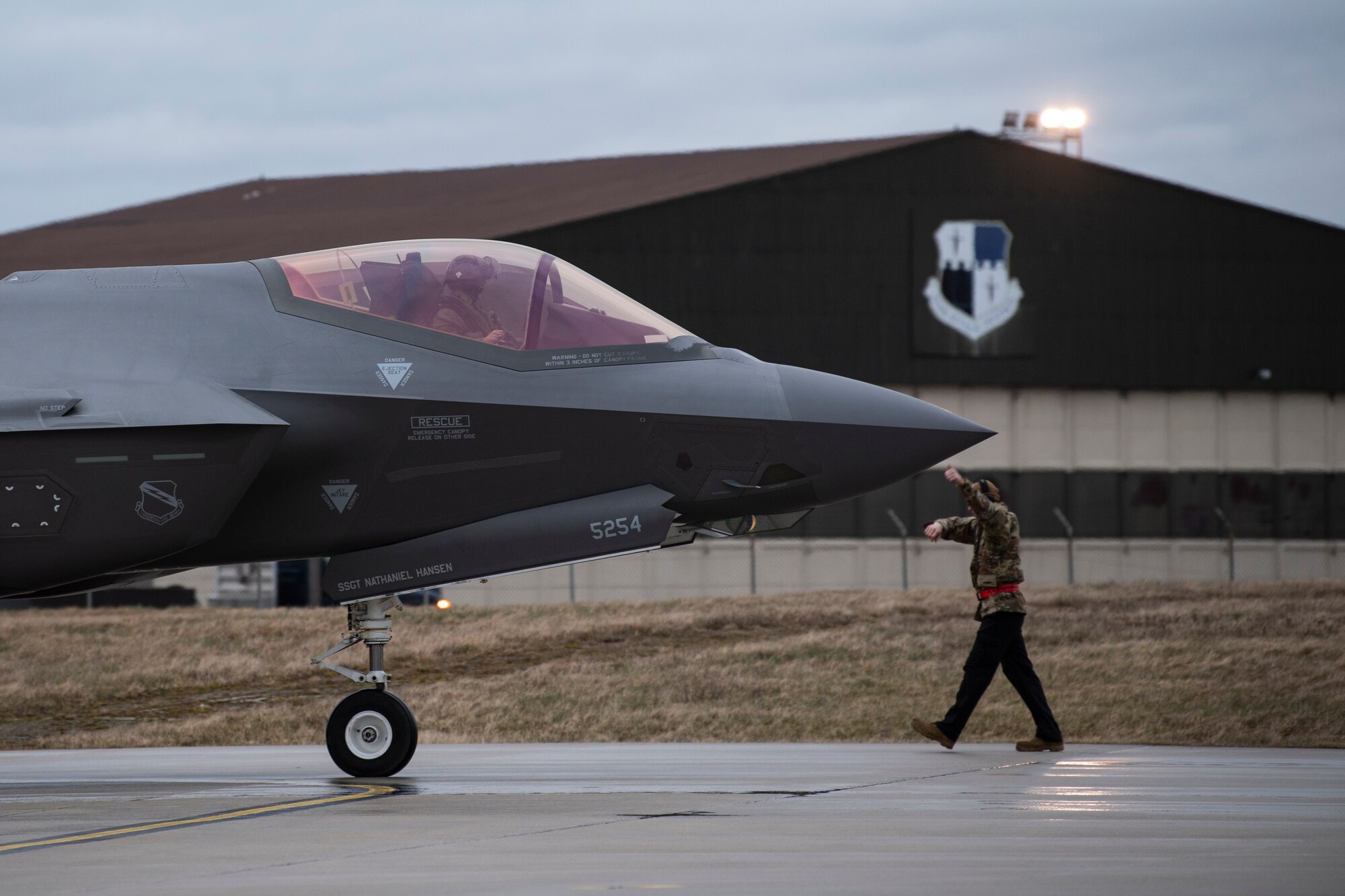 A U.S. Air Force aircraft maintainer signals to a U.S. Air Force F-35A Lightning II pilot from the 34th Fighter Squadron at Hill Air Force Base, Utah, after arriving at Spangdahlem Air Base, Germany, Feb. 16, 2022.