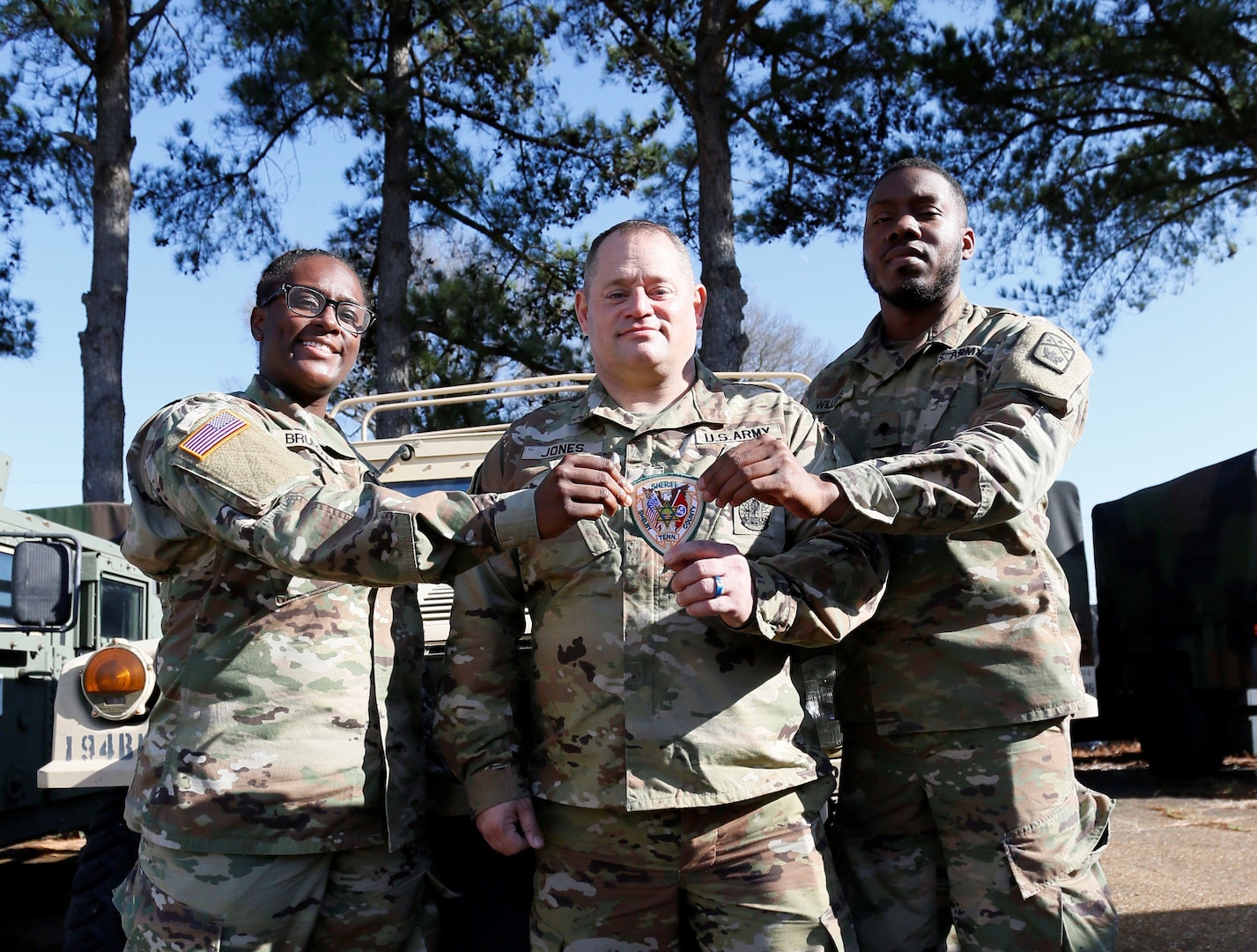 Spc. Daija Brunson, Sgt. 1st Class Jonathan Jones, and Spc. Christopher Williams hold a Shelby County Sheriff’s Office patch at the Millington National Guard Armory, Jan. 8. All three Soldiers are full-time deputies with the Shelby County Sheriff’s Office and members of the Tennessee National Guard’s 268th Military Police Company. They are three of more than 80 Soldiers who left Jan. 10 for a yearlong deployment to the Horn of Africa.