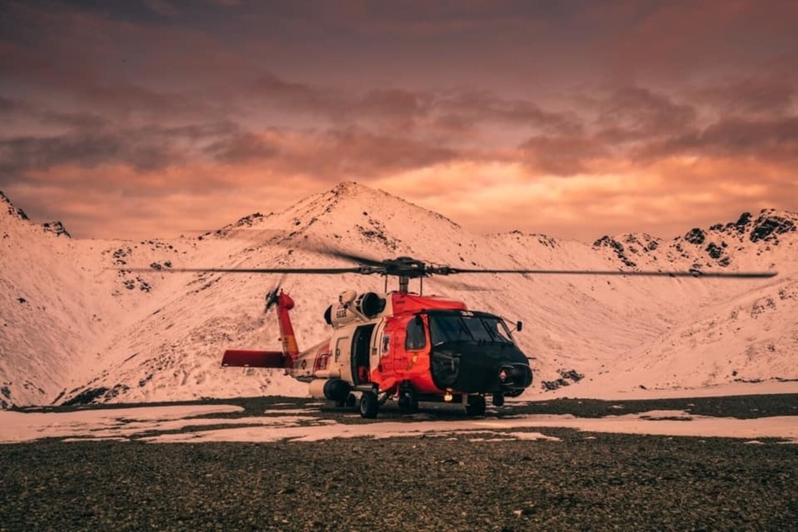 Coast Guard helicopter in front of a mountain at sunset