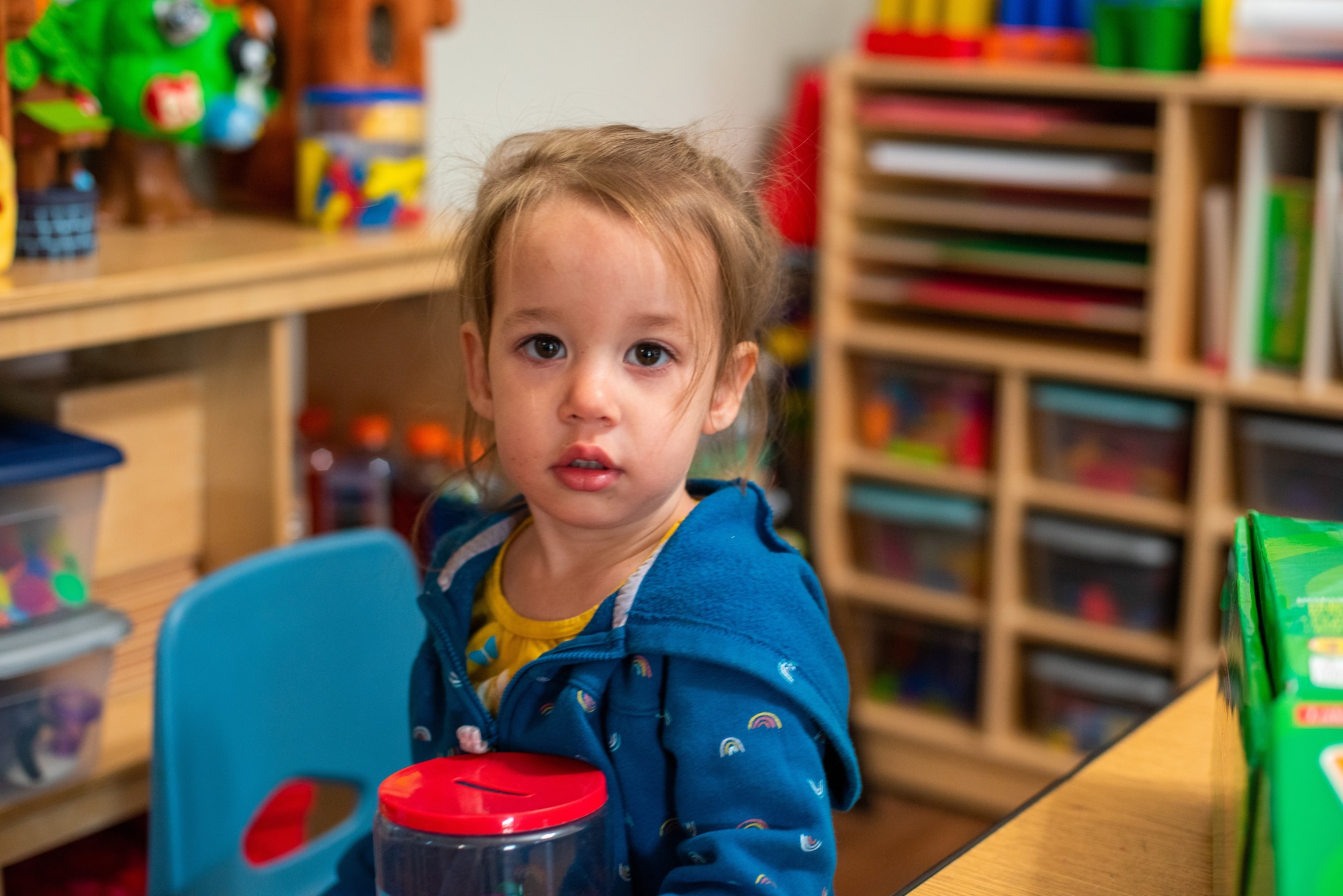 A photo of a child sitting in a classroom.