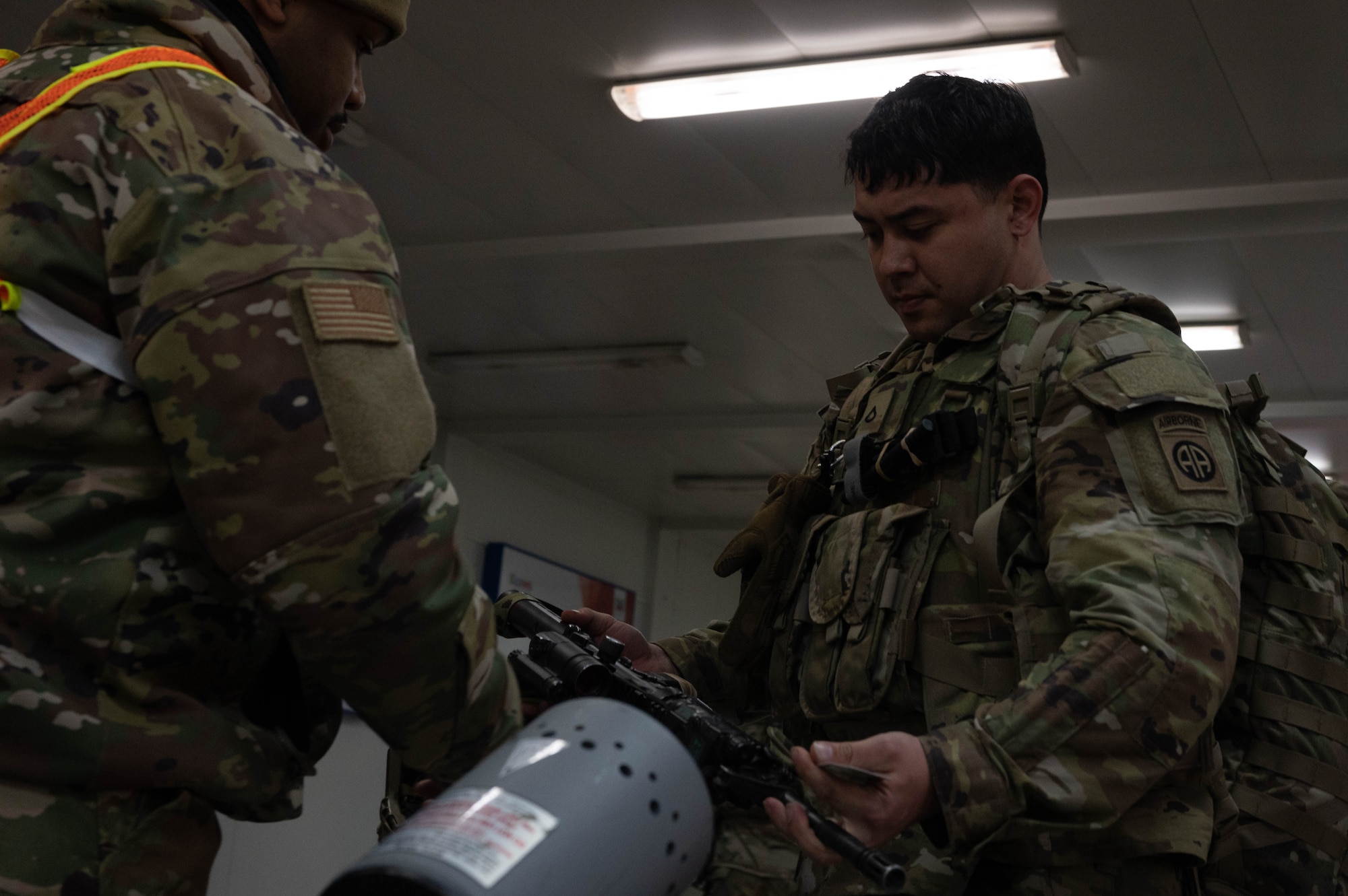 An Airman checks the chamber of a soldier's weapon.