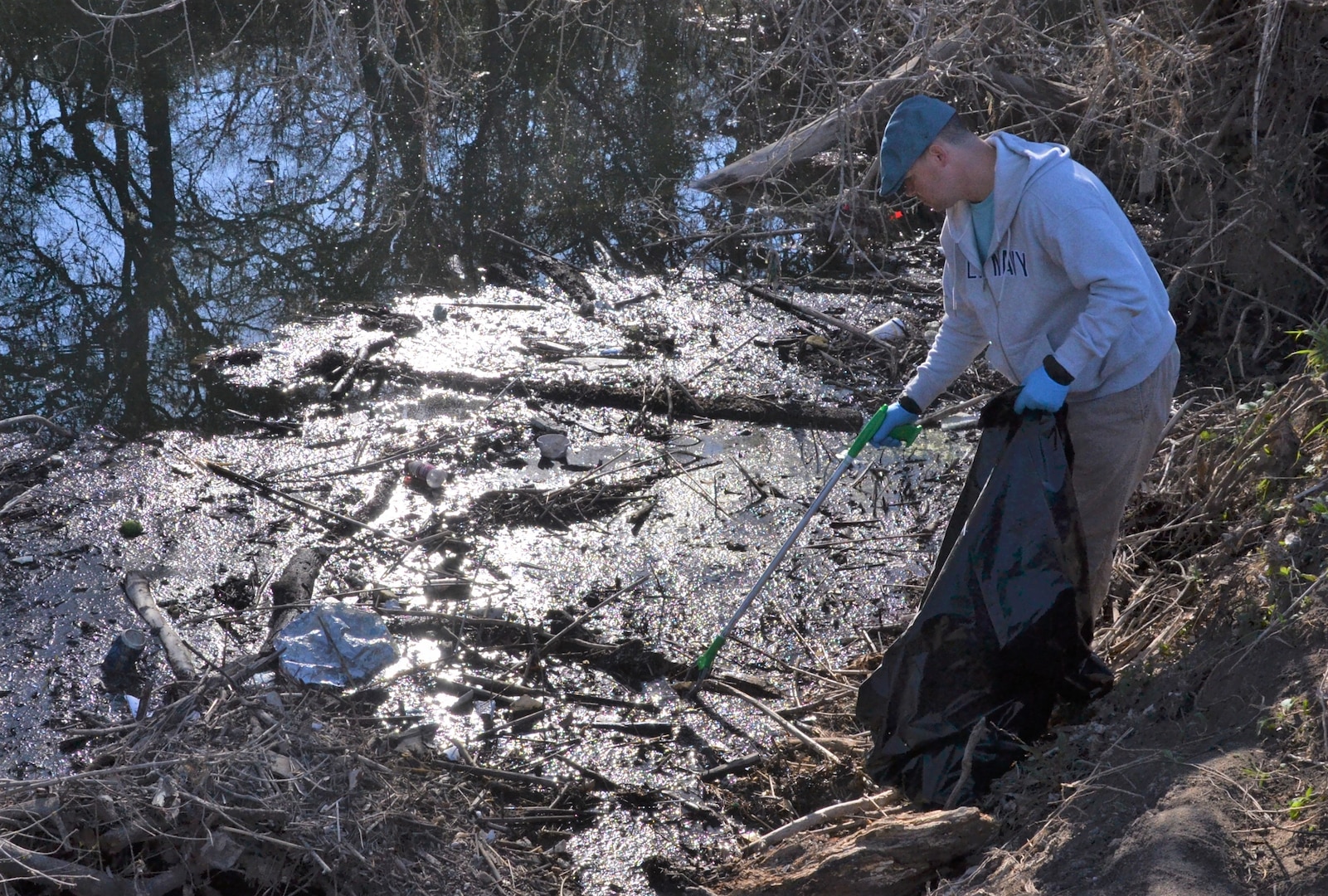 Man picks up trash from a creek.