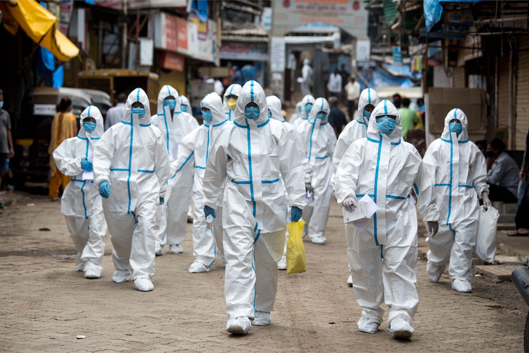 Health workers wearing personal protective equipment arrive to take part in a checkup camp at a slum in Malad during the
COVID-19 pandemic. (Shutterstock item: 1743306872. April 28, 2020)