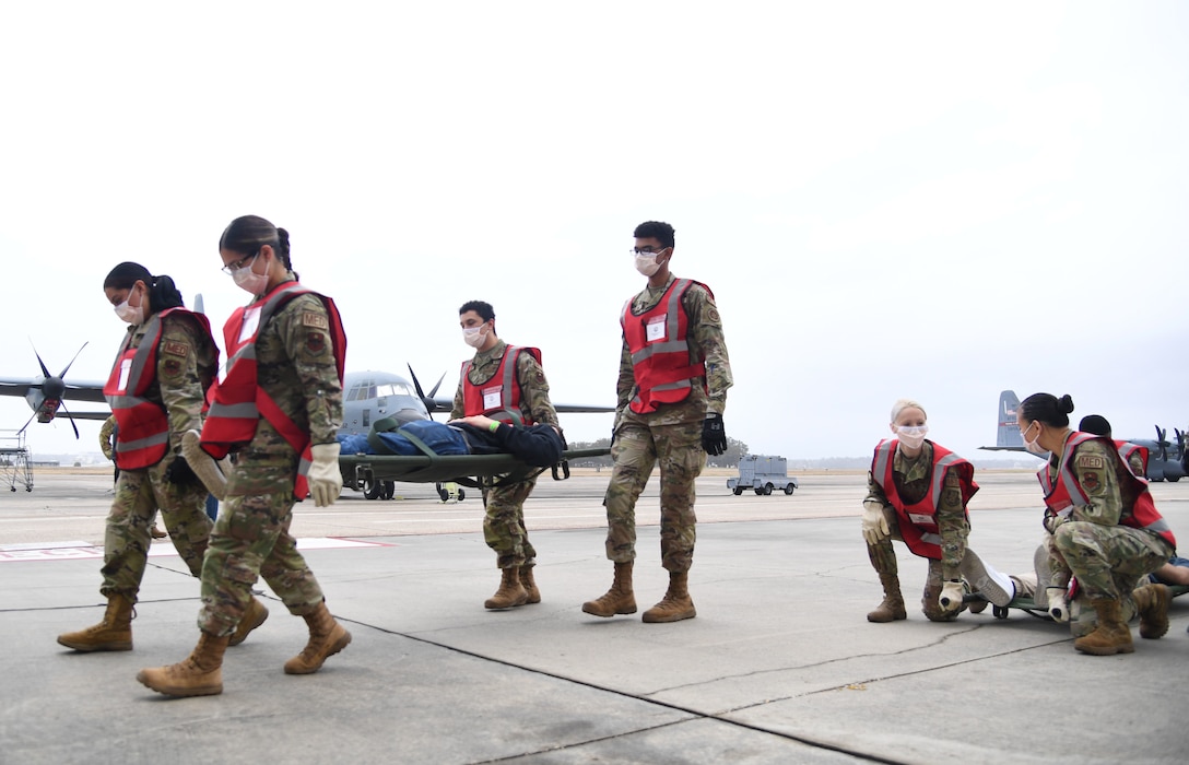 A group of airmen carry a simulated patient on a flightline.