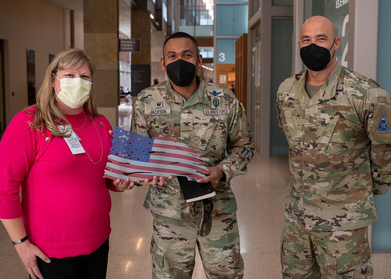 Eva Gergely, Center for Development and Civic Engagement chief with the Veterans Affairs Eastern Colorado Health Care System, U.S. Space Force Col. Marcus Jackson, Buckley Garrison commander, and U.S. Air Force Chief Master Sgt. Robert Devall, Buckley Garrison command chief, pose with a metal American flag at the Rocky Mountain Regional VA Medical Center in Aurora, Colo., Feb. 15, 2022. Jackson and Devall visited the medical center as part of National Salute to Veteran Patients Week which occurs the week of Feb. 14. (U.S. Space Force photo by Senior Airman Haley N. Blevins)
