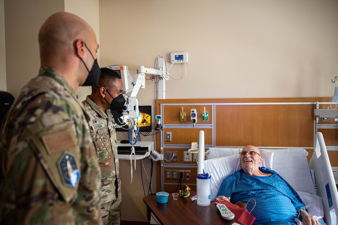 U.S. Space Force Col. Marcus Jackson, Buckley Garrison commander, and U.S. Air Force Chief Master Sgt. Robert Devall, Buckley Garrison command chief, speak to a veteran at the Rocky Mountain Regional VA Medical Center in Aurora, Colo., Feb. 15, 2022. Jackson and Devall visited the hospital to speak to veterans who are currently a part of in-patient care during National Salute to Veteran Patients Week. (U.S. Space Force photo by Senior Airman Haley N. Blevins)