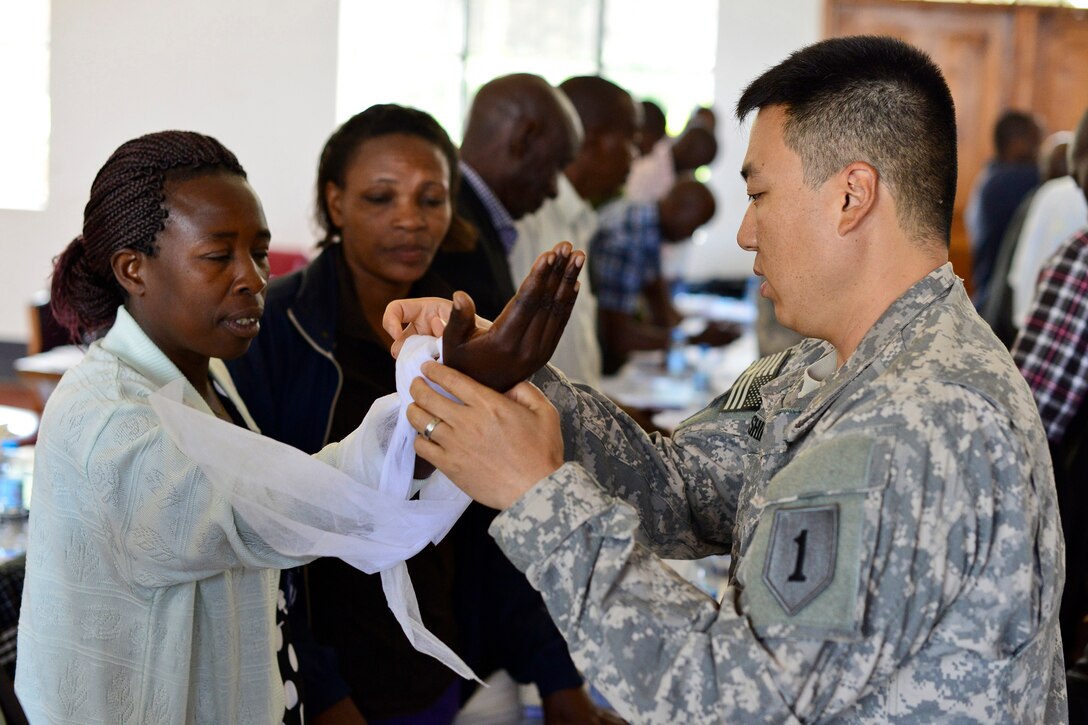 U.S. Army Capt. (Dr.) Jae Shim, with the 1st Combined Arms Battalion, 63rd Armor Regiment, 2nd Armored Brigade Combat Team, 1st Infantry Division, shows members of a village health team how to apply direct pressure to a wound during a One Health mission in Kabale, Uganda, Sept. 11, 2013