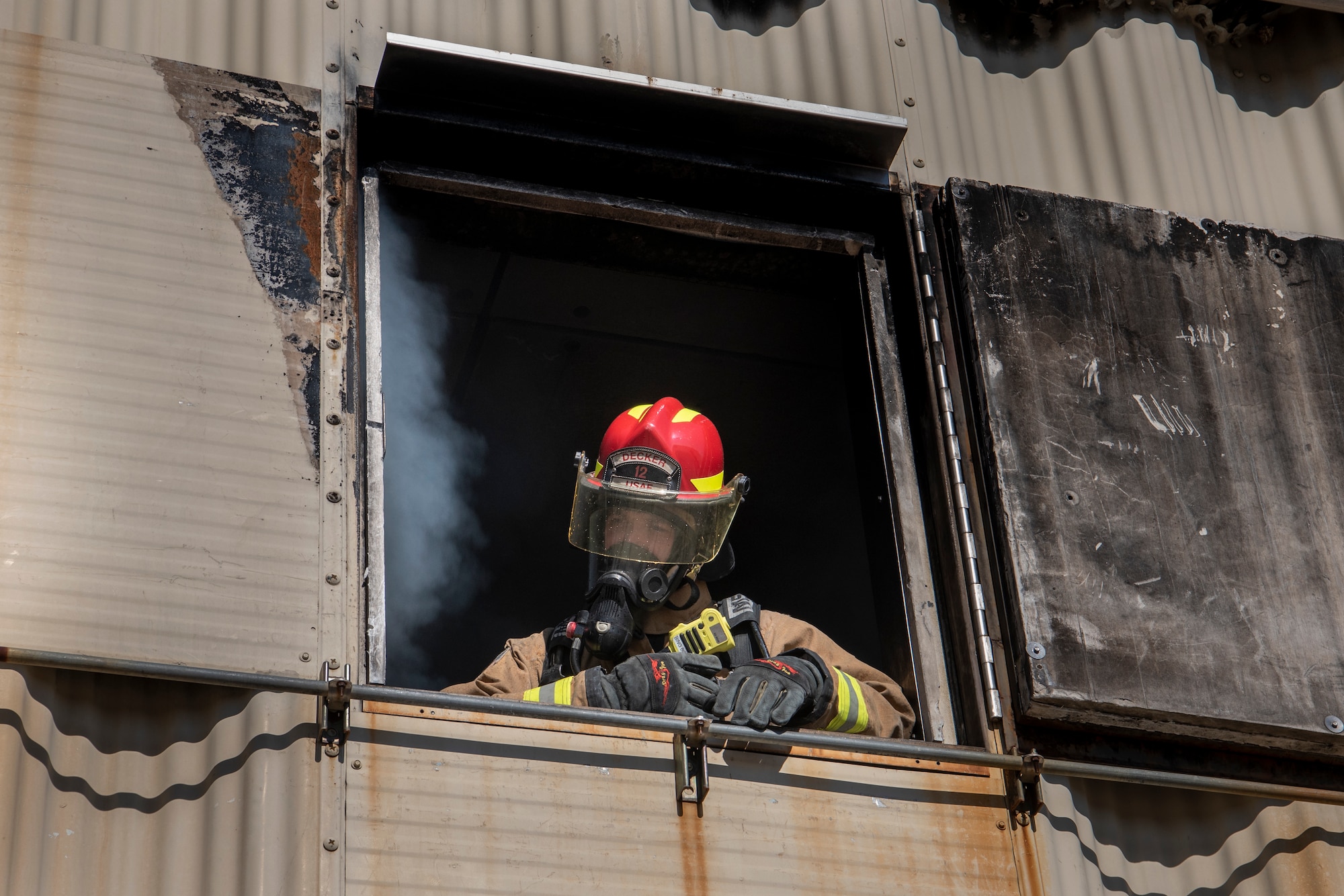 Tech. Sgt. Andrew Decker, 4th Civil Engineering Squadron firefighter, stands on the second floor of a burning building during a live-fire training exercise at Seymour Johnson Air Force Base, North Carolina, Feb. 10, 2022. Firefighters train in smoky conditions to learn how to properly use their equipment. (U.S. Air Force courtesy photo by Airman 1st Class Hadley Neish)