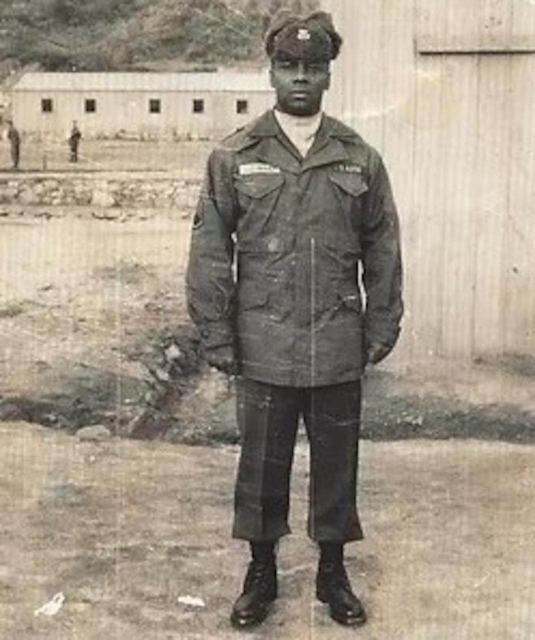 A man in uniform and winter cap poses for a photo.