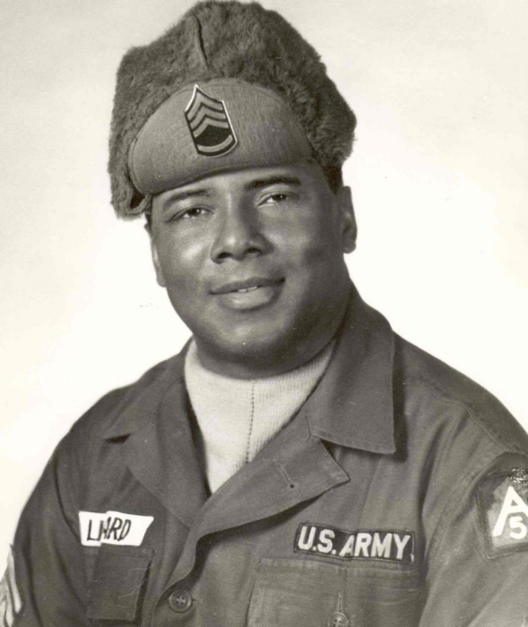 A man in uniform and winter cap poses for a photo.