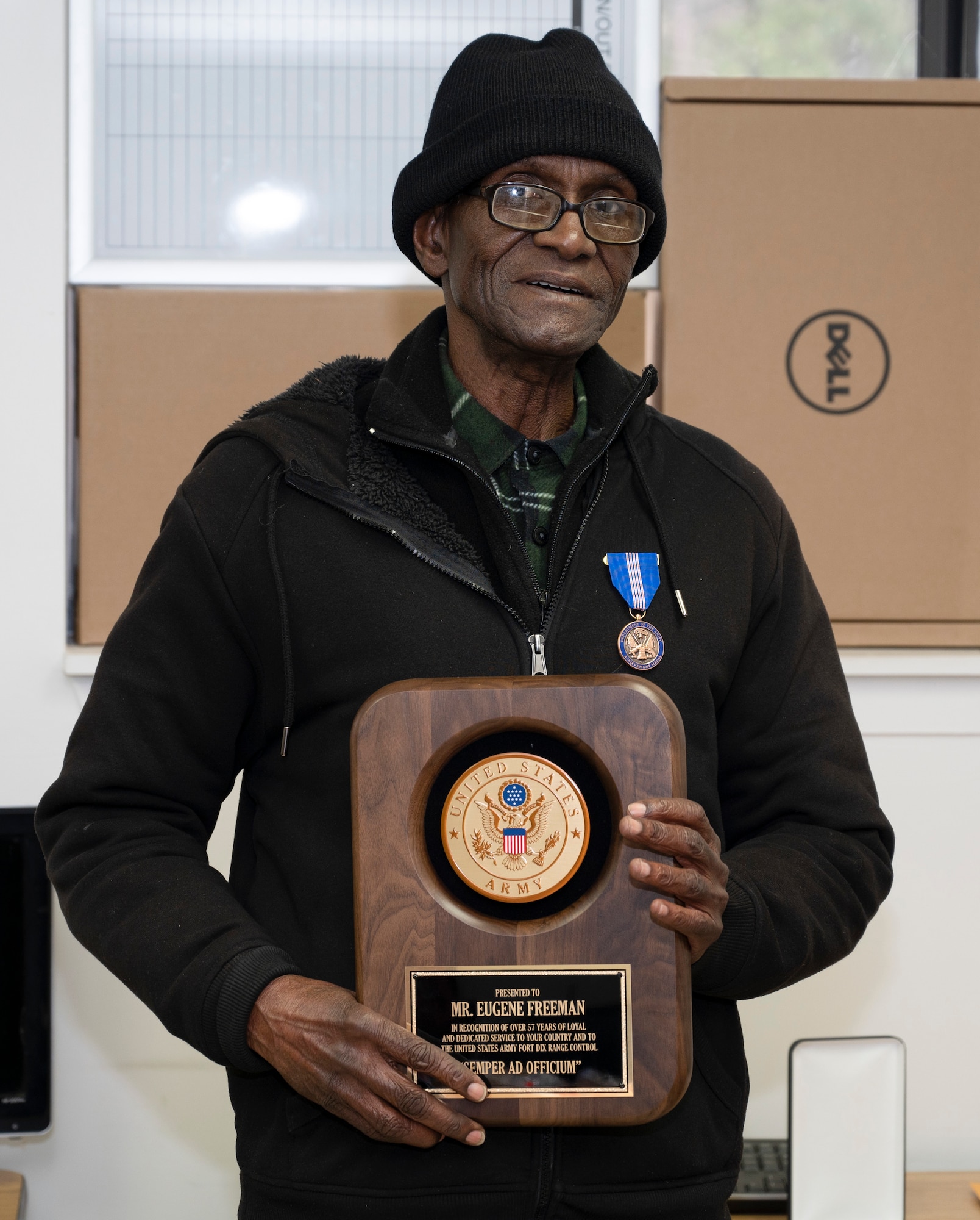 Eugene Freeman, Army Support Activity-Fort Dix Training Division carpenter, poses with an award during his retirement ceremony on Joint Base McGuire-Dix-Lakehurst, N.J., Feb. 24, 2022. Freeman is the division’s longest term employee having served more than 50 years. He originally joined the military after being drafted into the Vietnam War, after returning to New Jersey he continued serving the U.S. as a civilian. (U.S. Air Force photo by Senior Airman Ariel Owings)