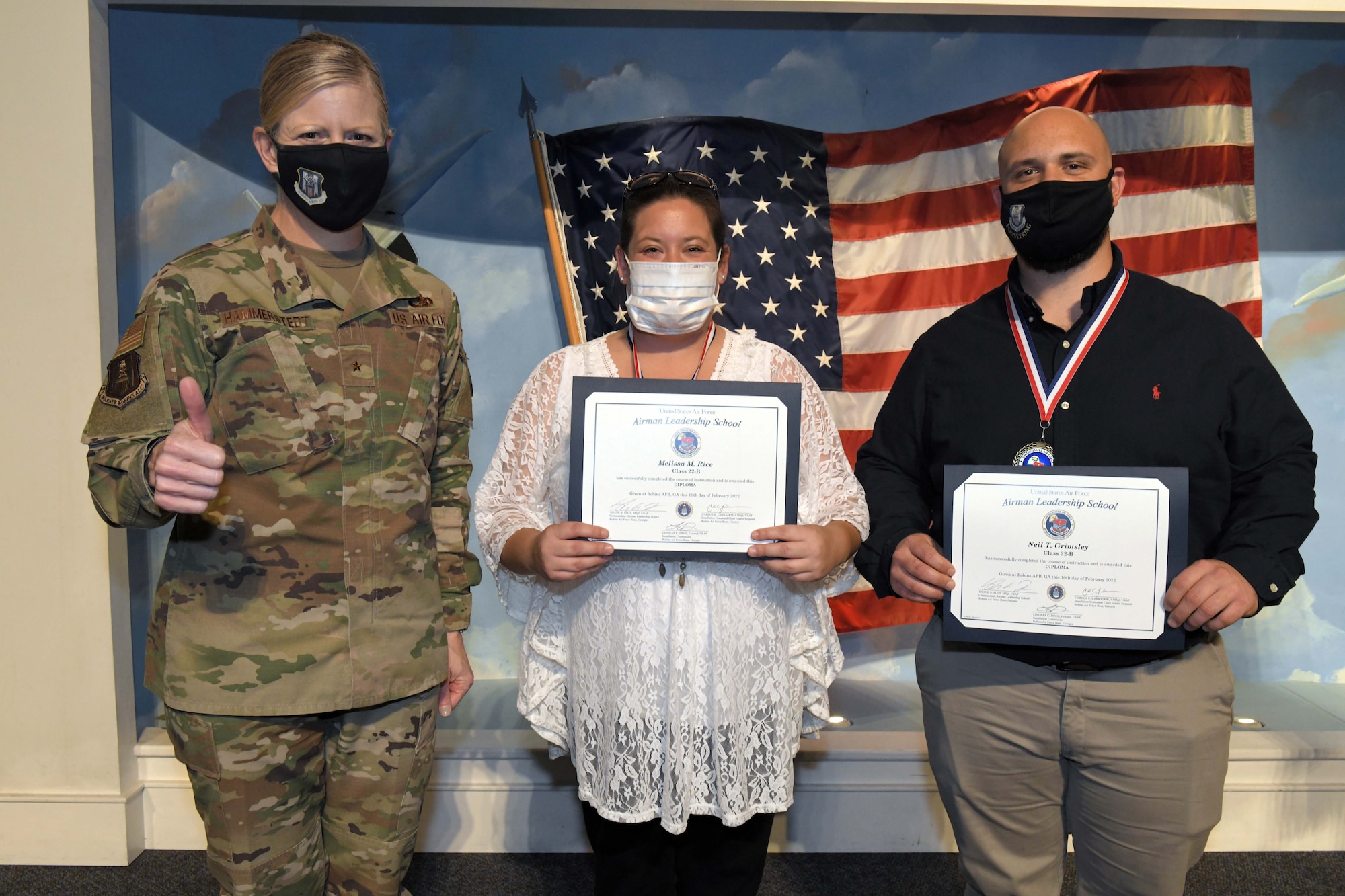 Photo shows individuals standing with certificates and "thumbs up"