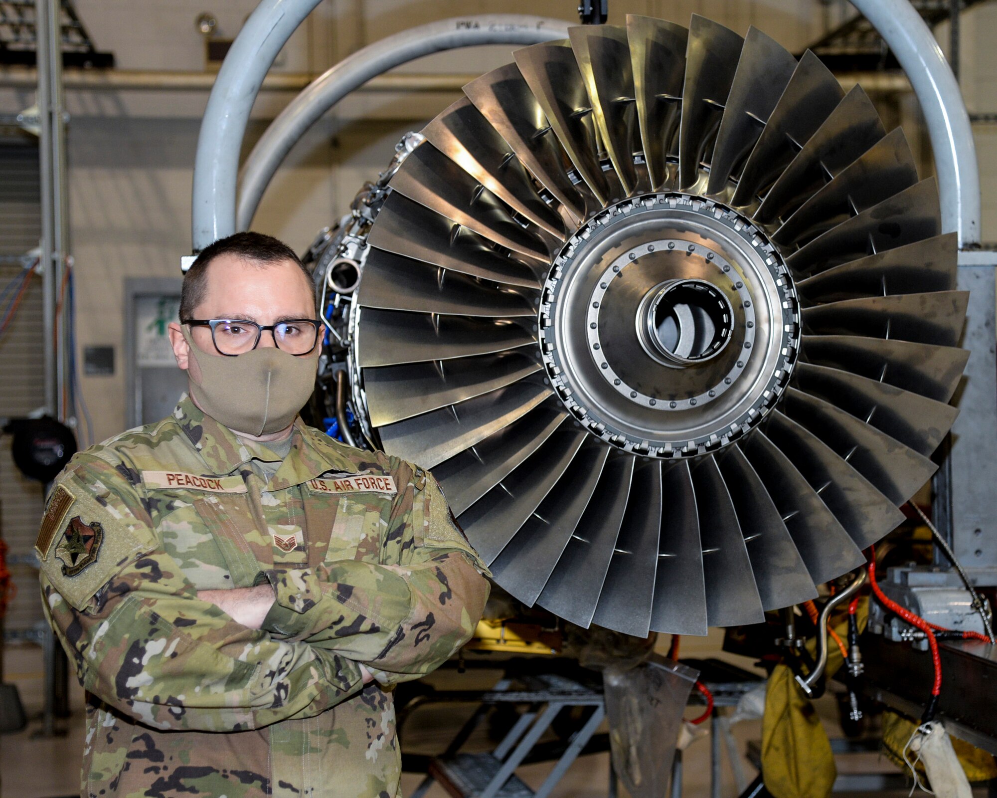 An image of U.S. Air Force Staff Sgt. Lewis Peacock, 177th Maintenance Group engine mechanic, posing with a General Electric F110 turbofan engine.