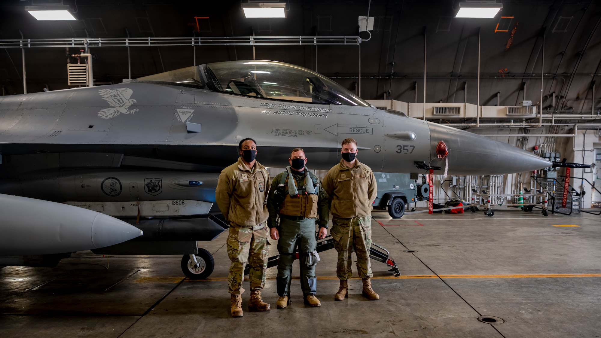 Airmen posing in front of an F-16 Fighting Falcon.