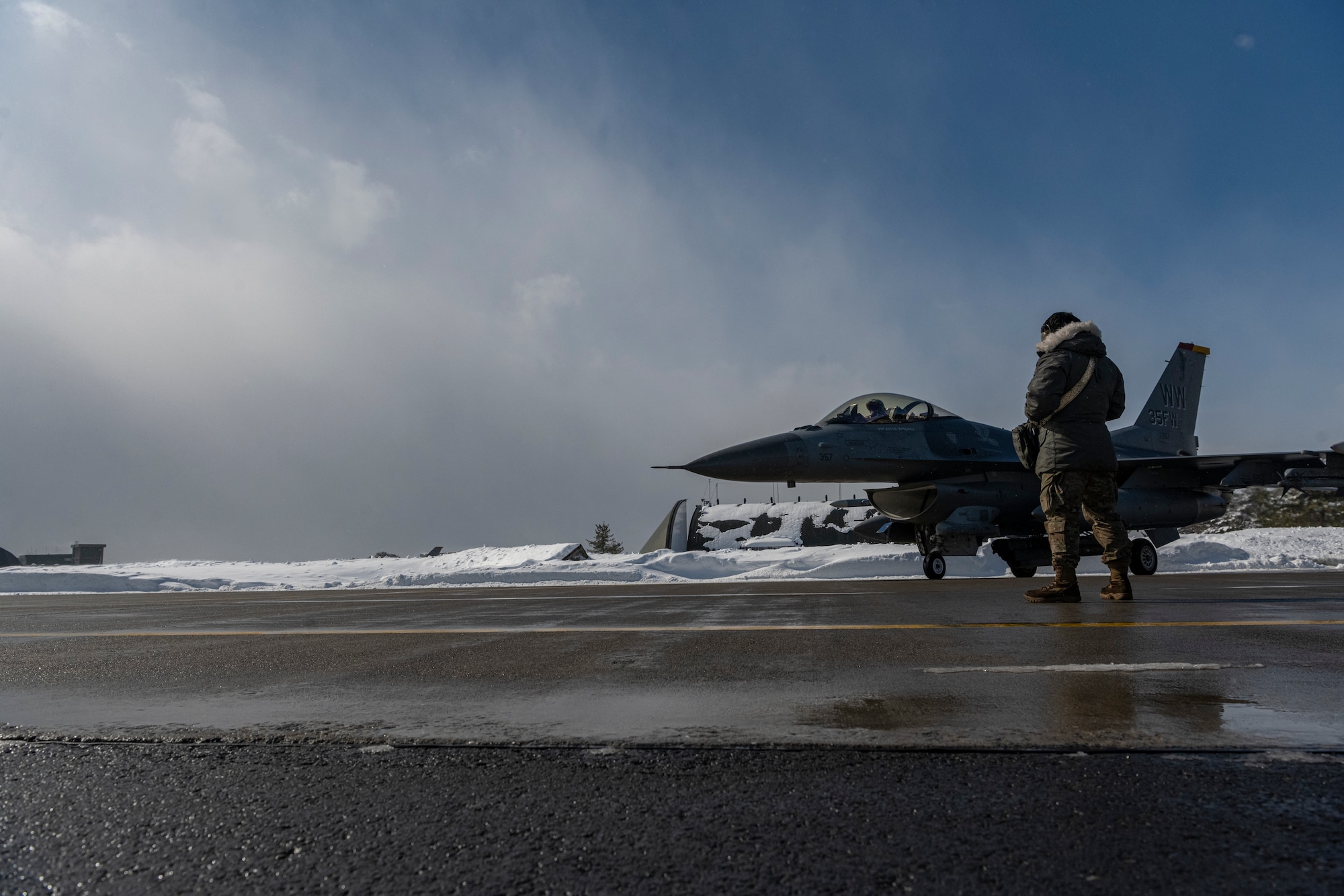 Airman standing on the flightline waiting for a jet to taxi to runway.