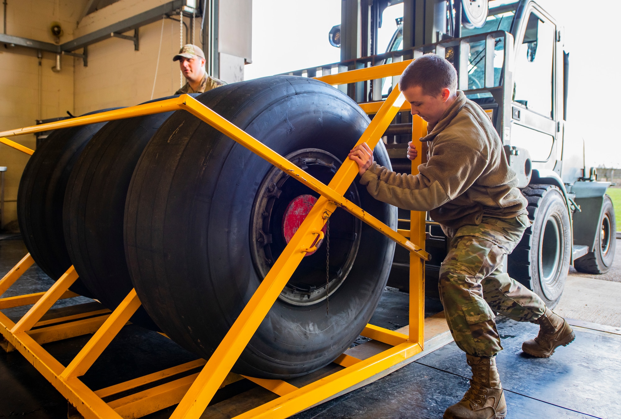 Airmen from the 100th Aircraft Maintenance Squadron unload a rack of C-17 Globemaster III aircraft wheels from a forklift at Royal Air Force Mildenhall, England, Feb. 24, 2022. Although the wheels belong to aircraft from RAF Brize Norton, Airmen from the 100th AMXS are providing support to our host nation partner by preparing them for disassembly in order for new tires to be installed. (U.S. Air Force photo by Senior Airman Kevin Long)