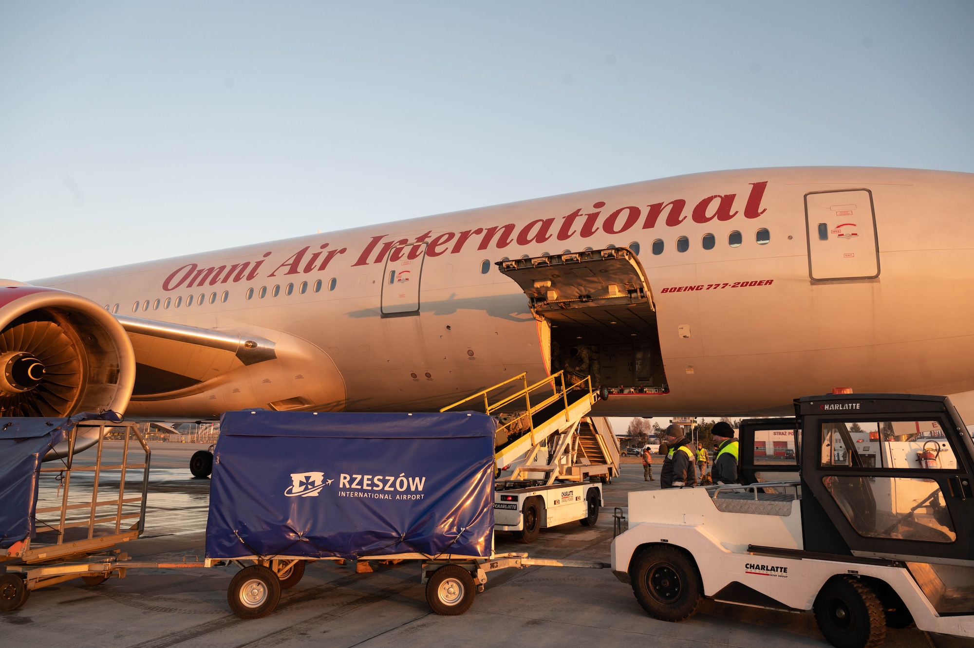 Baggage pallets line up next to a Boeing 777 aircraft at Rzeszow-Jasionka airport.