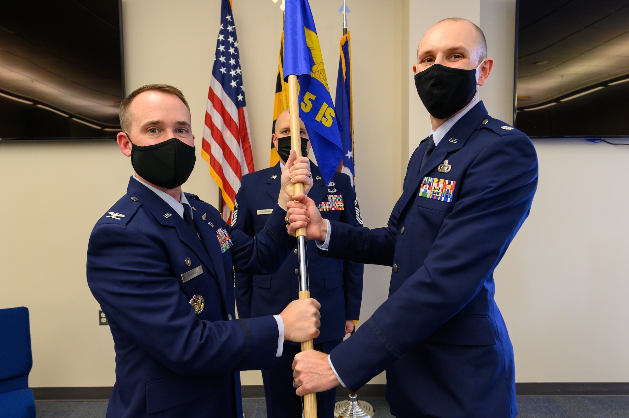 (From left) Air Force Col. Reid Novotny, the commander for the 175th Cyber Operations Group, passes the 135th Intelligence Squadron guidon to U.S. Air Force Lt. Col. John Ippoliti, incoming 135th IS commander, Feb. 12, 2022, during a change of command ceremony for the 135th IS at Warfield Air National Guard Base at Martin State Airport, Middle River, Maryland. The passing of the guidon symbolizes the passing of command from one service member to another. (U.S. Air National Guard photo by Staff Sgt. Sarah M. McClanahan)