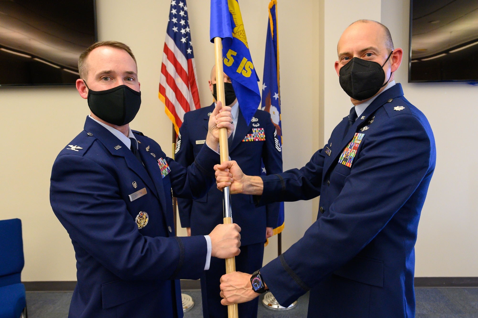 (From left) Air Force Col. Reid Novotny, the commander for the 175th Cyber Operations Group, recieves the 135th Intelligence Squadron guidon from U.S. Air Force Lt. Col. Jason R. Barrass, outgoing 135th IS commander, Feb. 12, 2022, during a change of command ceremony for the 135th IS at Warfield Air National Guard Base at Martin State Airport, Middle River, Maryland. The passing of the guidon symbolizes the passing of command from one service member to another. (U.S. Air National Guard photo by Staff Sgt. Sarah M. McClanahan)