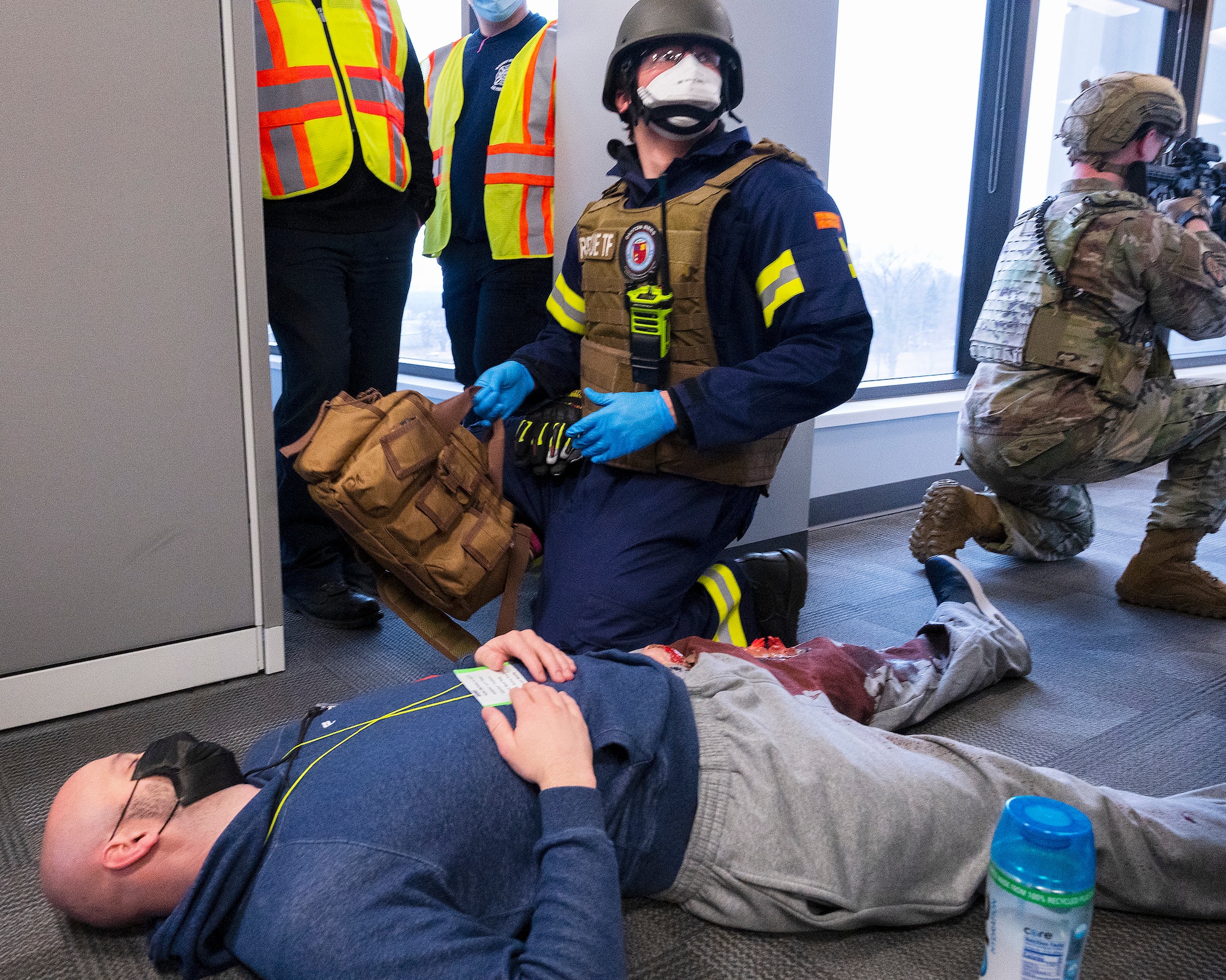 A paramedic with the rescue task force checks on a shooting “victim” as an 88th Security Forces Squadron Defender provides cover and exercise observers look on during an active-shooter exercise Feb. 23, 2022, at Wright-Patterson Air Force Base, Ohio. The exercise gave first responders, including police, fire and medical personnel, the opportunity to practice coordinating emergency actions and procedures. (U.S. Air Force photo by R.J. Oriez)