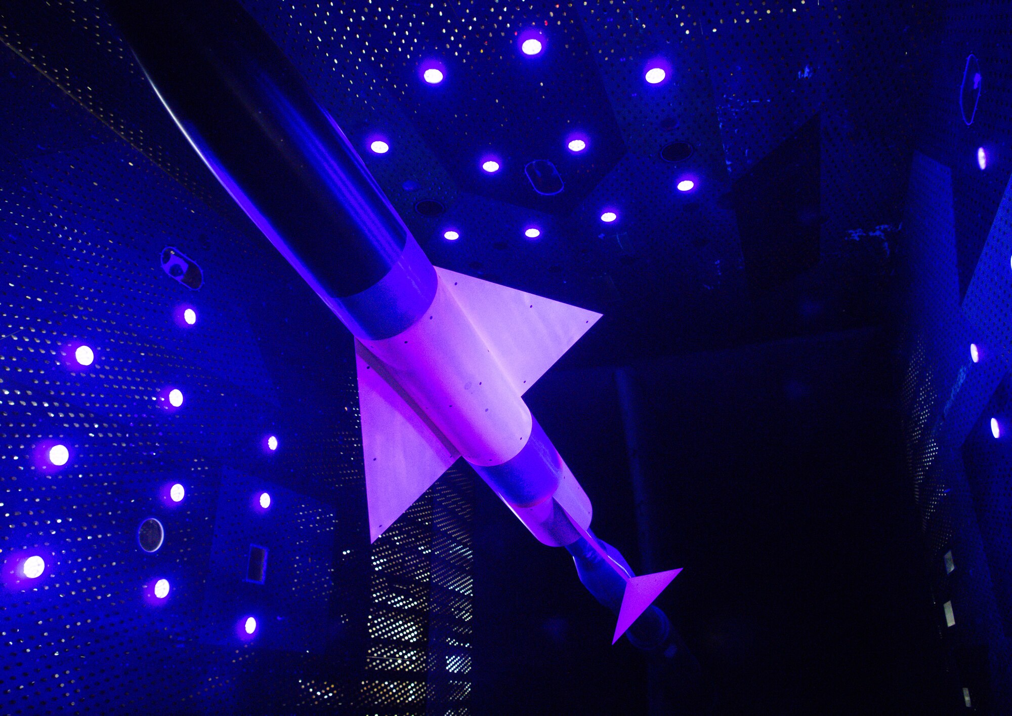 An AGARD-C model coated in pressure-sensitive paint (PSP) is seen here mounted on a sting in the 16-foot transonic wind tunnel at Arnold Air Force Base, Tenn.