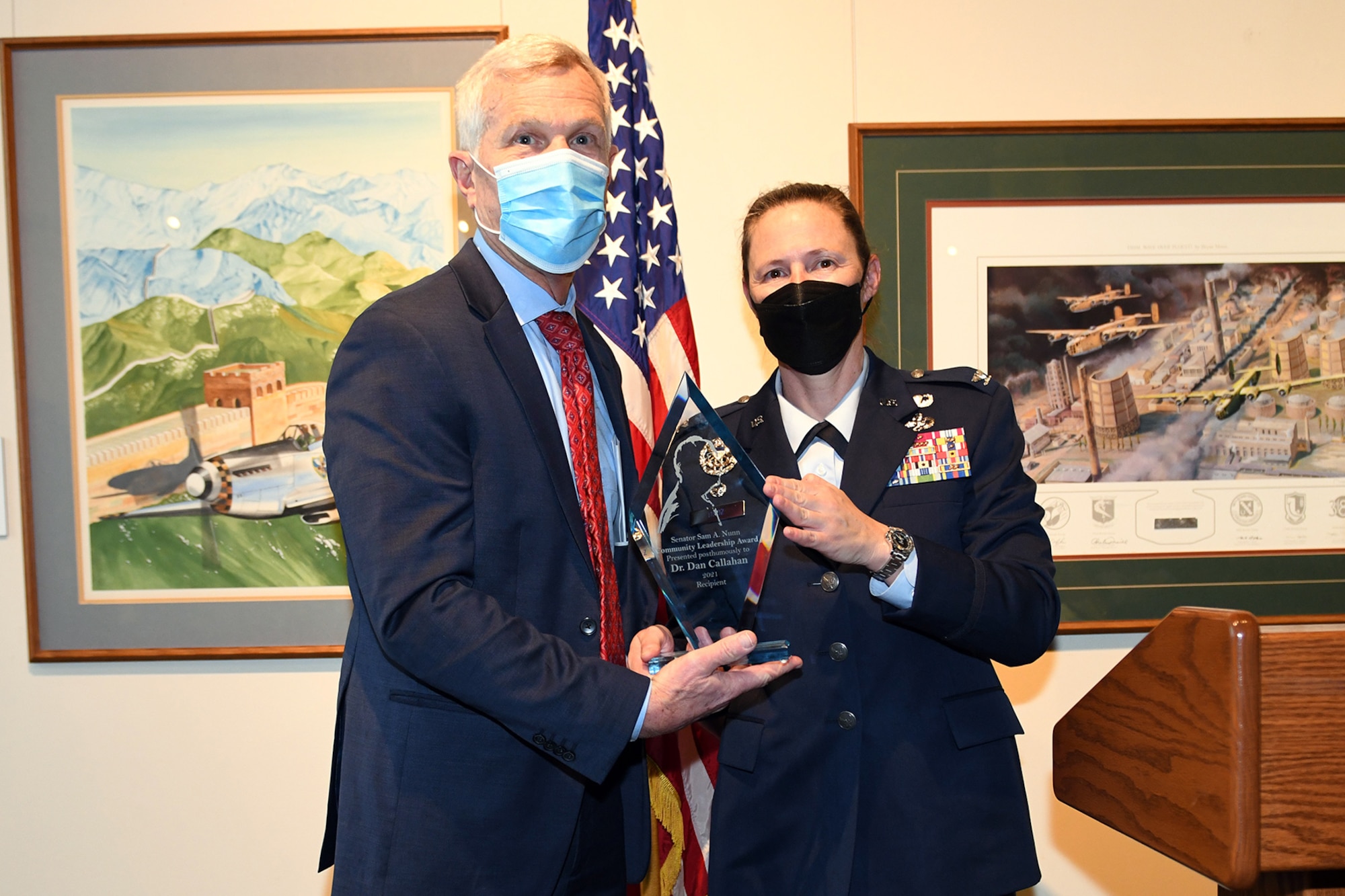 Photo shows two individuals standing holding a trophy.