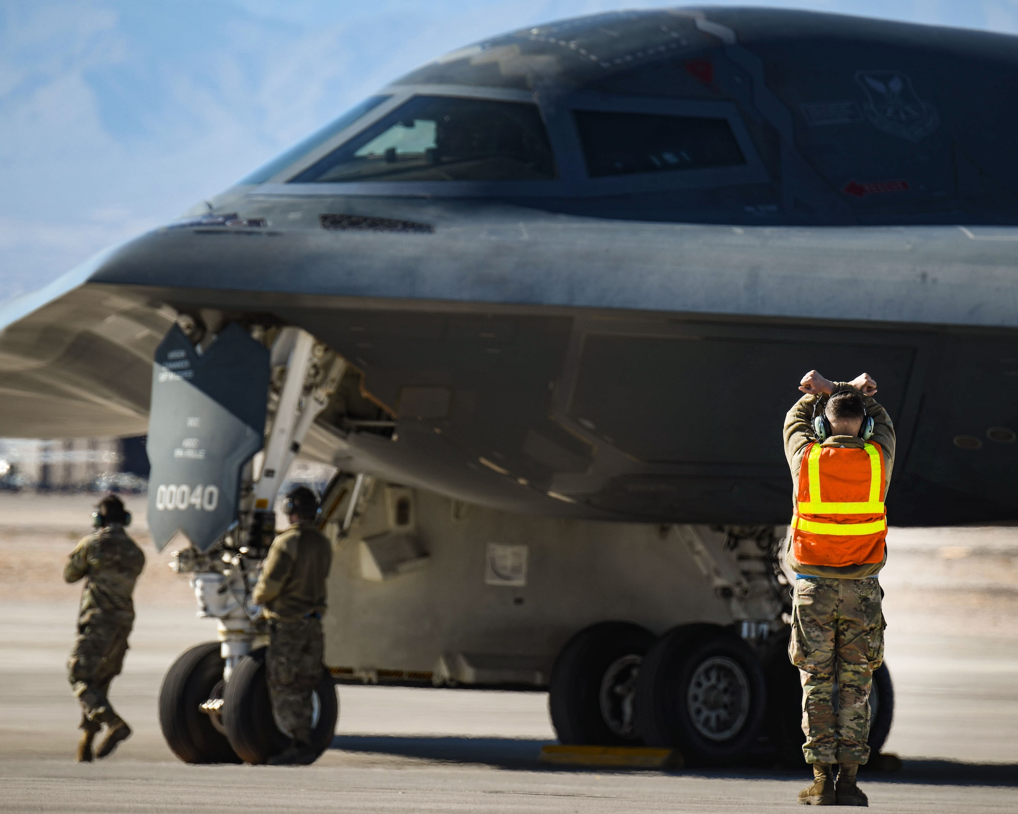 A crew chief marshals a B-2 Spirit at Nellis Air Force Base.