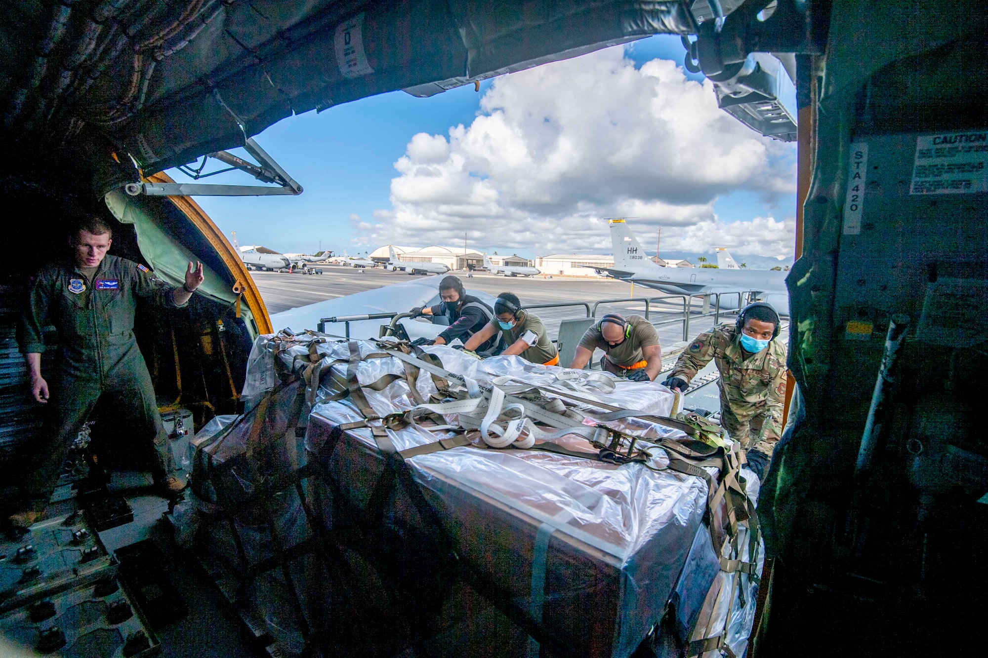 Cargo specialists from the 735th Air Mobility Squadron (AMS) and 48th Aerial Port Squadron (APS) load cargo onto a KC-135 while at Joint Base Pearl Harbor-Hickam, Jan. 20, 2022.