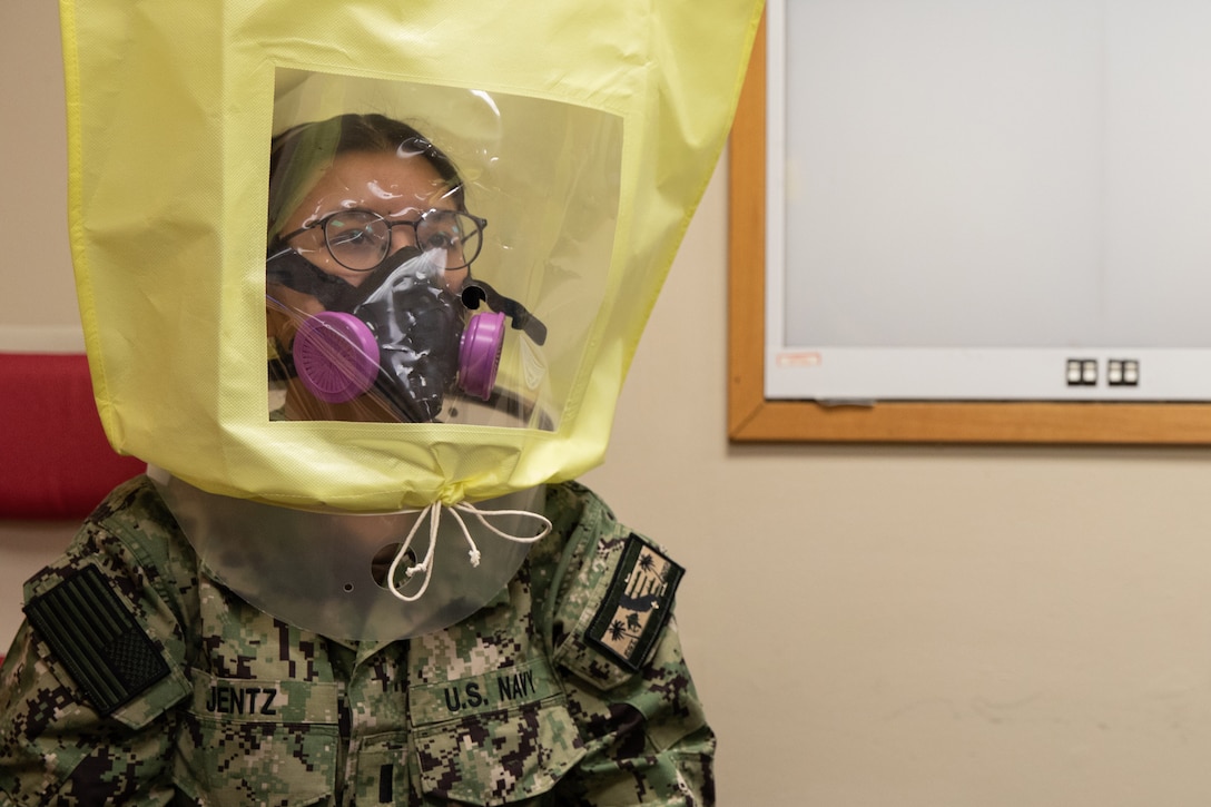A sailor sits with protective gear over her head.