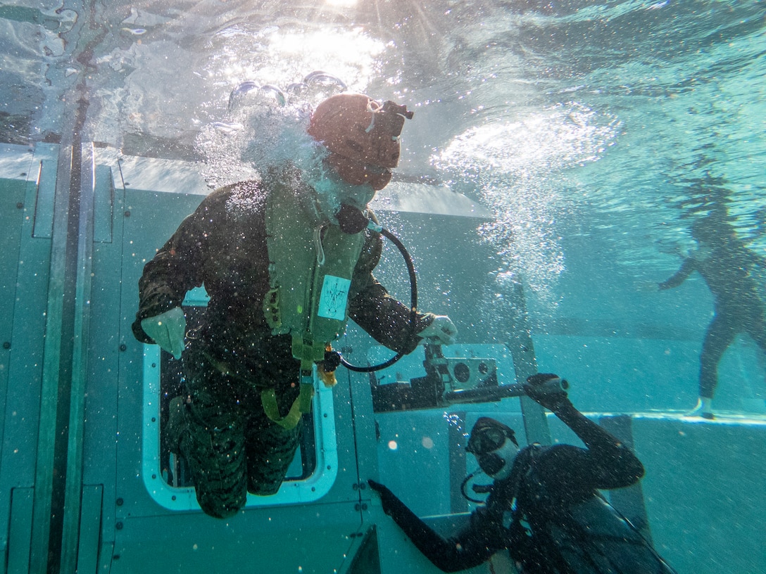 A U.S. Marine with 1st Radio Battalion, I Marine Expeditionary Force Information Group, egresses from an emergency exit during Underwater Egress Survival Training on Marine Corps Base Camp Pendleton, California, Oct. 28, 2021. UET provides Marines with life-saving skills to safely evacuate a submerged aircraft in the event of an emergency. (U.S. Marine Corps photo by Lance Cpl. Austin Gillam)