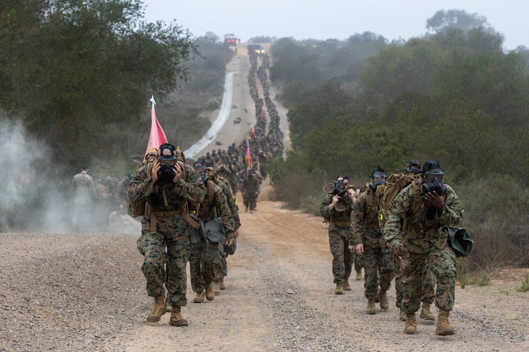 U.S. Marines with 1st Radio Battalion, I Marine Expeditionary Force Information Group, participate in a simulated chemical, biological, radiological, nuclear attack during the 1st Radio Battalion Food Drive Hike at Marine Corps Base Camp Pendleton, Nov 19, 2021. Through consistent physical and technical training, Marines sustain basic combat skills and knowledge to be successful on the battlefield. (U.S Marine Corps photo by Cpl. Nicolas Atehortua)