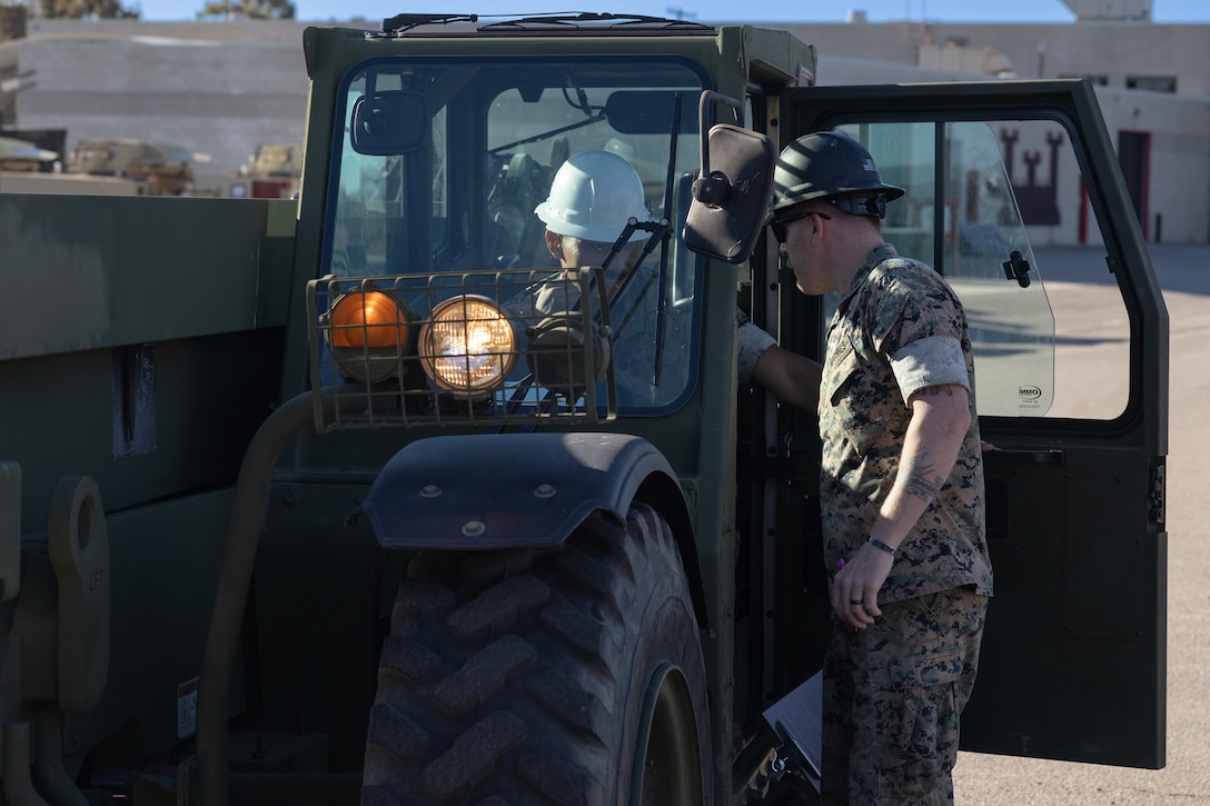 U.S. Marine Corps Lance Cpl. Rene Fernandez, a Heavy Equipment Mechanic and Sgt Michael Harster, a Engineer Equipment Operator with 9th Communication Battalion, I Marine Expeditionary Force Information Group, review the events conducted during the Extended Boom ForkLift and Millennium Military Vehicle operators course at Marine Corps Base Camp Pendleton, California, Oct. 28, 2021. 9th Comm uses the EBFL/MMV operators course to train heavy equipment operators and encourage operational readiness solutions.