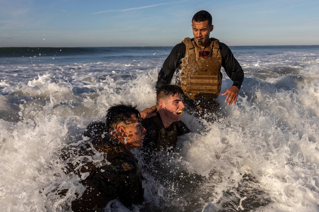U.S. Marine Corps Sgt. Kishahn Hobley (right) a Martial Arts Instructor Trainer with 1st Intelligence Battalion, I Marine Expeditionary Force Information Group supervises his students as they grapple in the ocean surf during a Martial Arts Instructor course led by 1st Intelligence Battalion, I MIG on Marine Corps Base Camp Pendleton, California, Dec. 16, 2021. The Marines participated in the MAI course to become instructors where they can train and advance Marines in the Marine Corps Martial Arts Program.  (U.S. Marine Corps photo by Cpl. Austin Gillam)