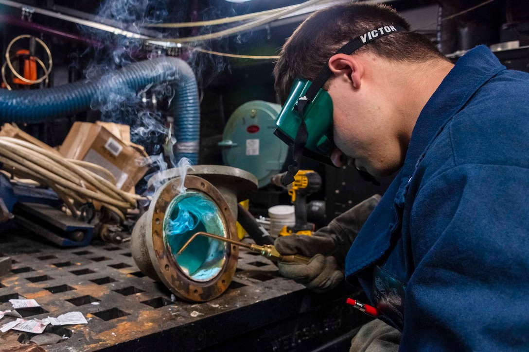 A sailor welds a piece of equipment.