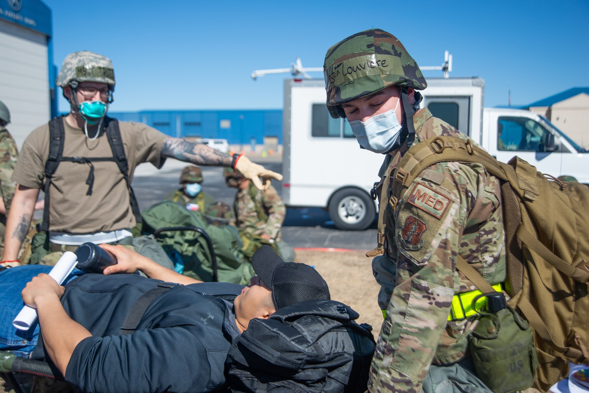 Airmen move a stretcher carrying personnel with artificial injuries into a simulated bunker.
