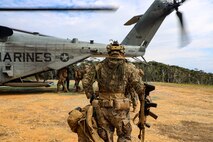 Marine holding backpack walking towards plane