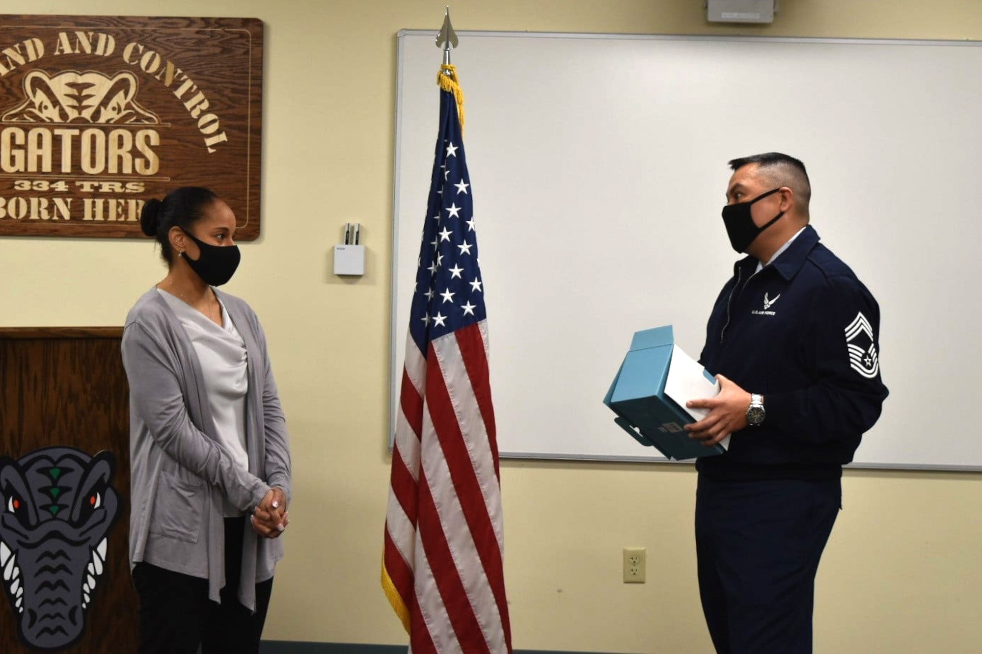 U.S. Air Force Chief Master Sgt. Timothy Garcia, Headquarters Air Force command post career field functional manager, the Pentagon, Virginia, presents Master Sgt. Desiree McIntyre, 403rd Wing command and control technician, with a gift inside Cody Hall at Keesler Air Force Base, Mississippi, Feb. 14, 2022. Garcia celebrated McIntyre's 30 years of dedication to the command post career field. (U.S. Air Force photo by Senior Airman Seth Haddix)