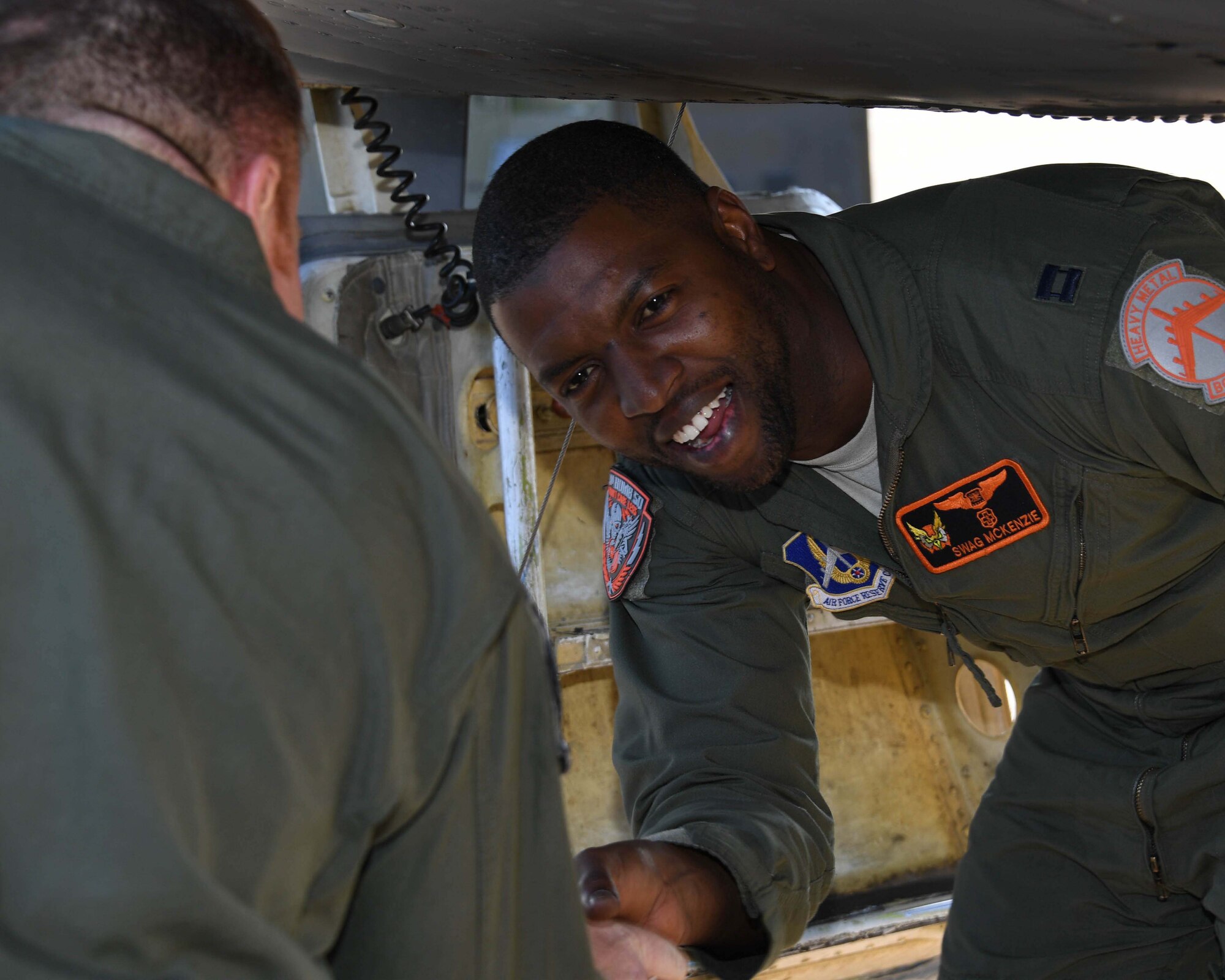 An Airman smiles from below an aircraft.