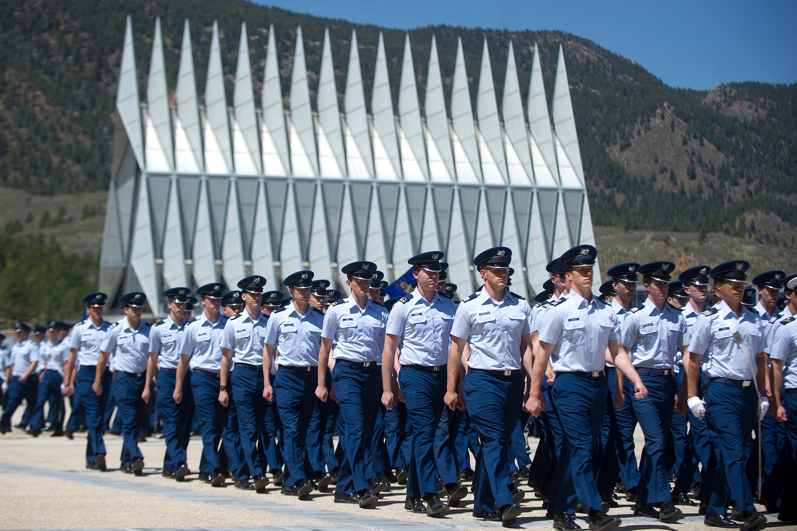 Many uniformed individuals march in a formation.