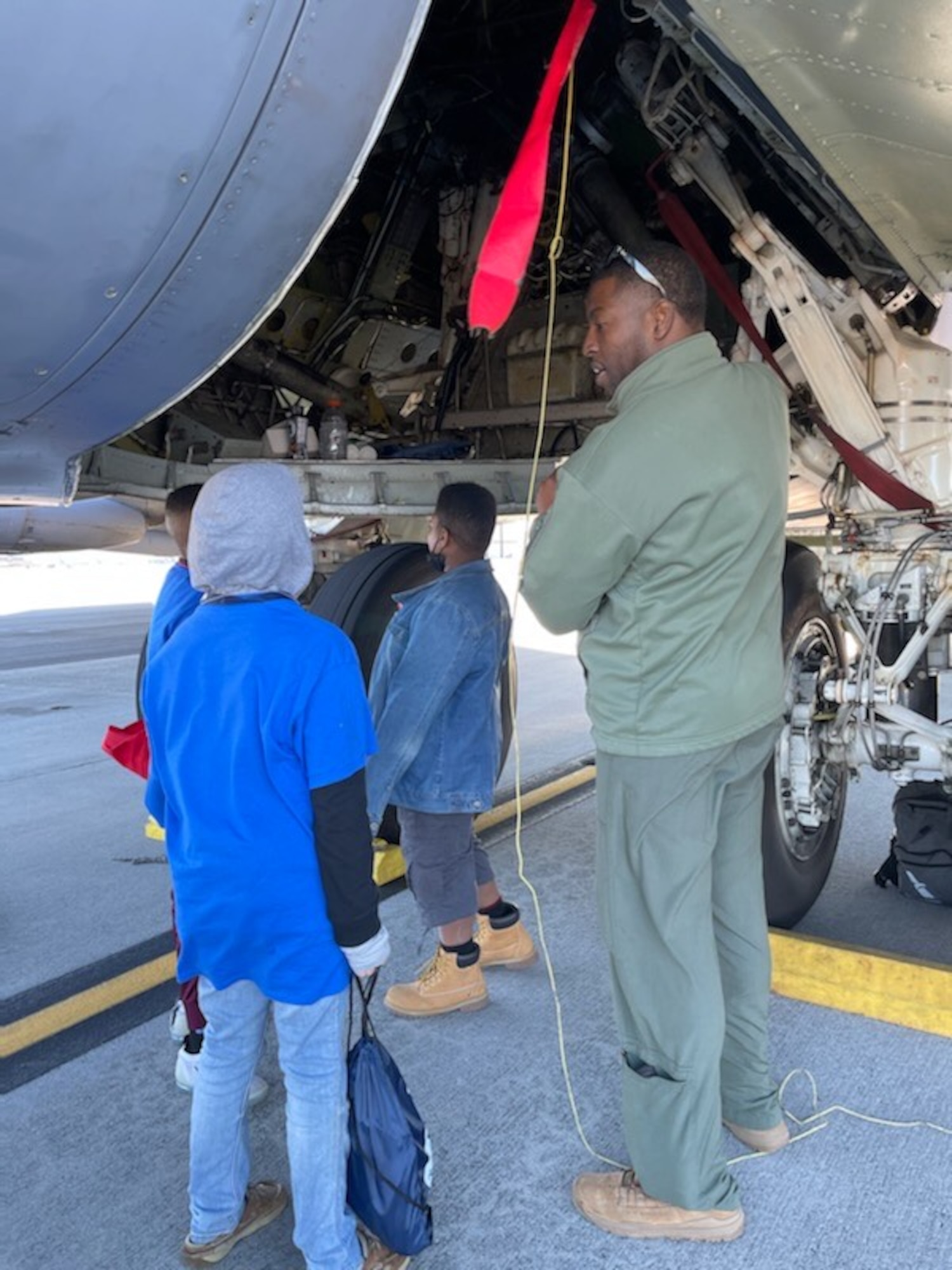An Airman talks to children near an aircraft.