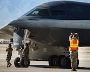 A crew chief marshals a B-2 Spirit at Nellis Air Force Base.