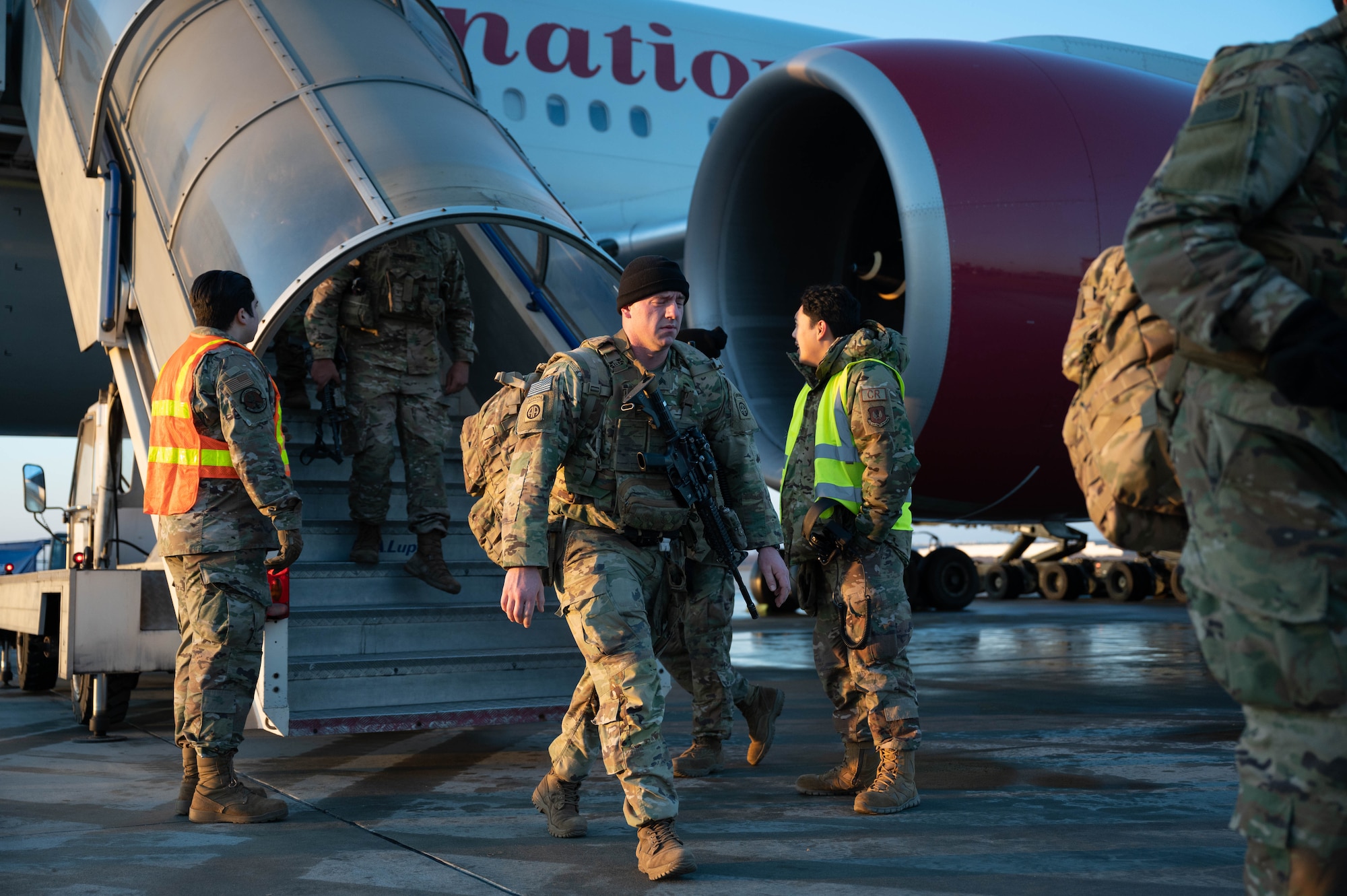 Soldiers depart a Boeing 777 commercial aircraft.