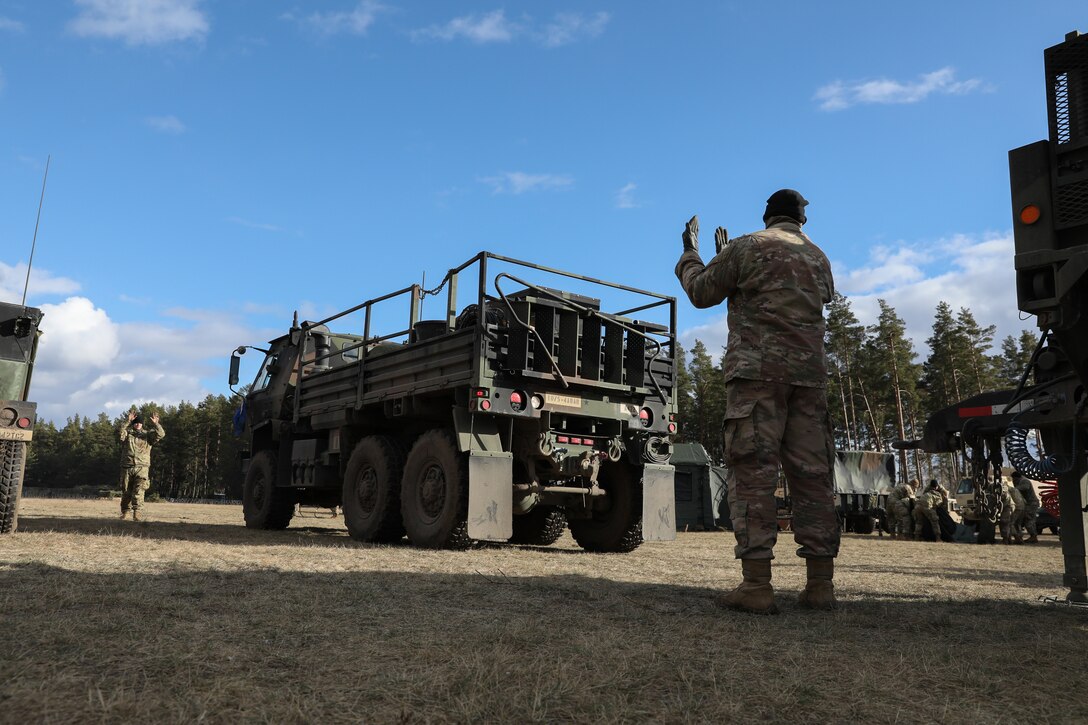 A soldier directs truck movement.